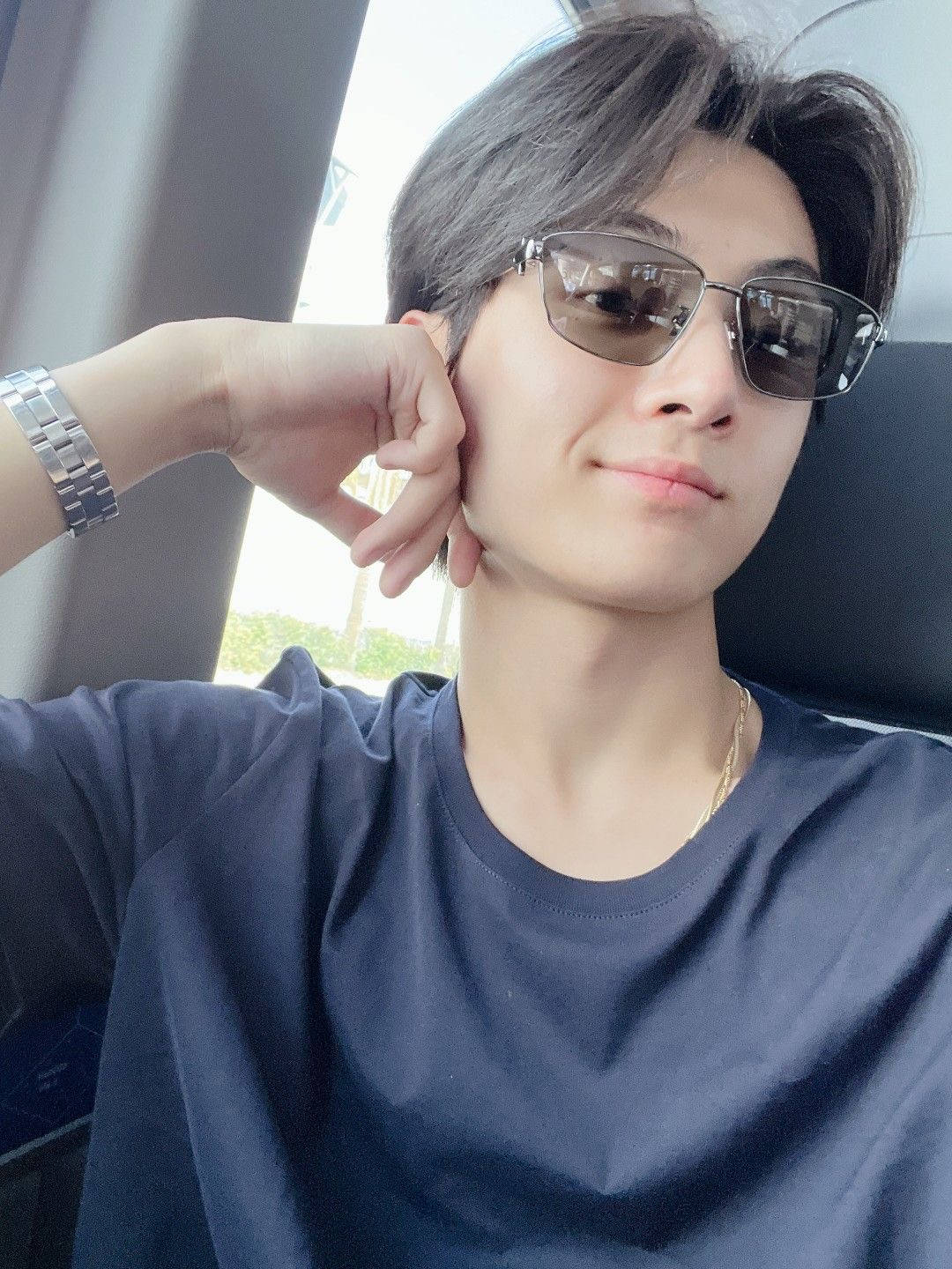 戴太陽眼鏡和穿海軍藍襯衫的年輕男子在車內擺姿勢。