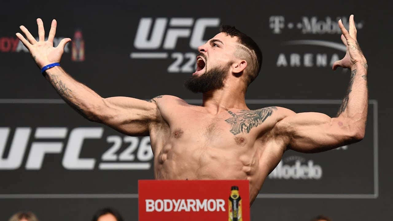  壁紙 — 一位肌肉發達、身上有紋身的UFC拳手在稱重活動中高舉雙臂，發出勝利的咆哮。