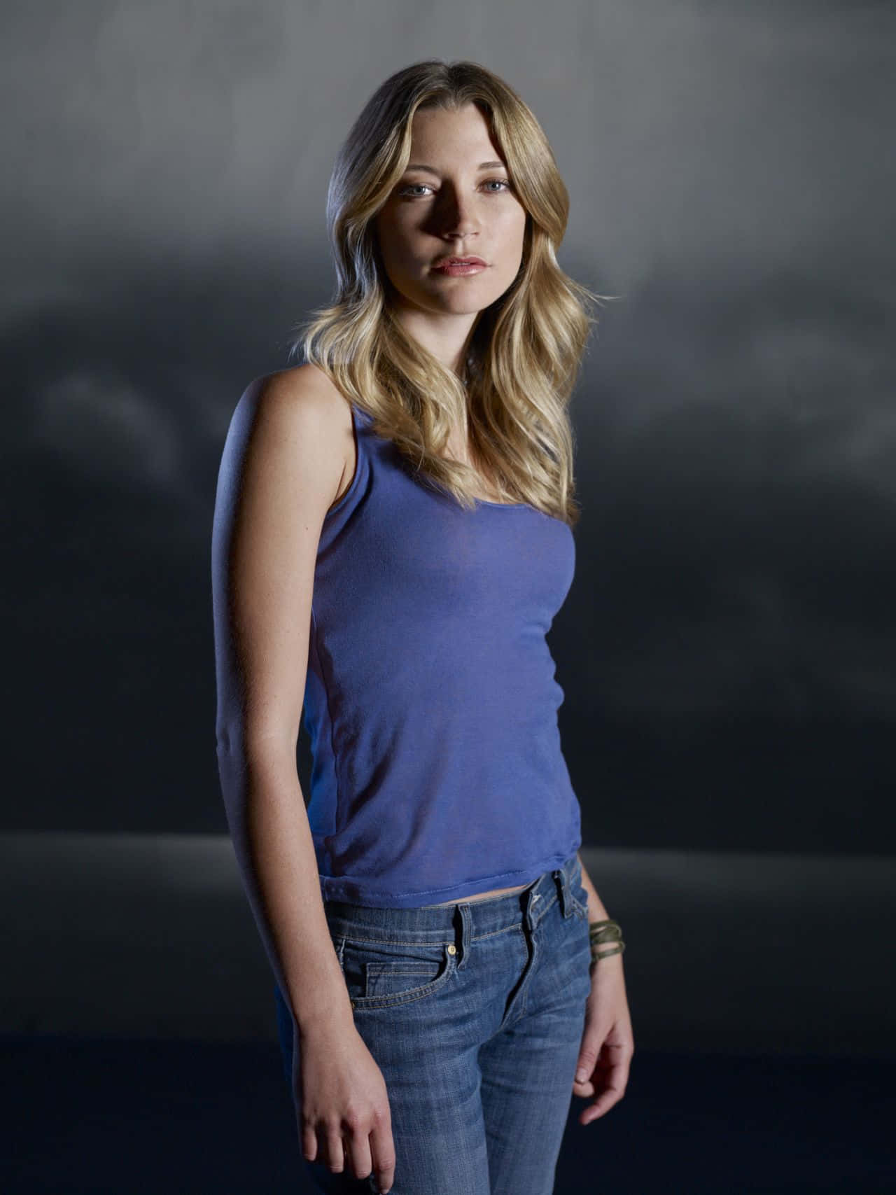Sarah Roemer 桌布 壁紙 — 一位金髮女性穿著藍色背心和牛仔褲，背景是深灰色攝影棚。