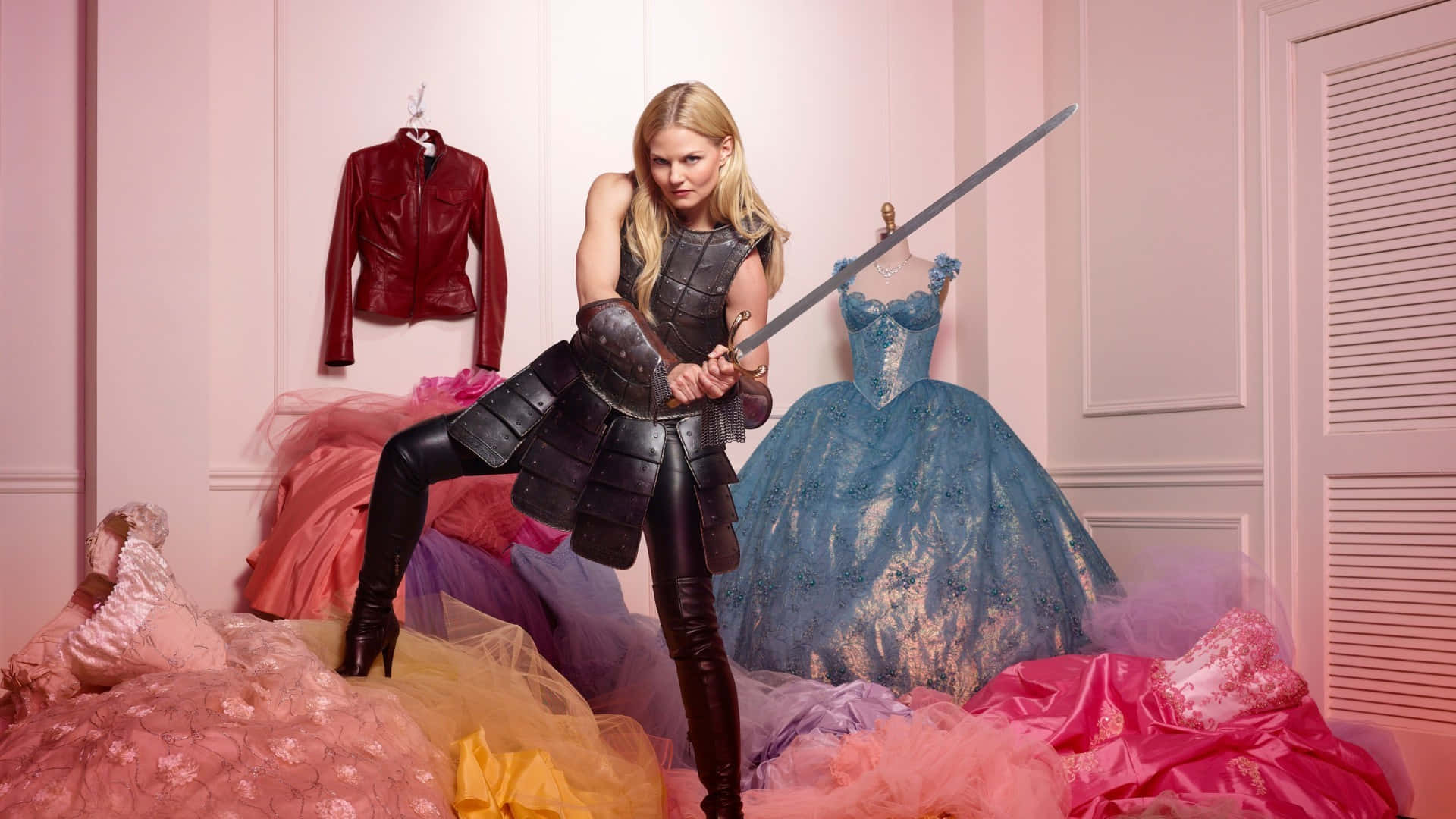 jennifer morrison 桌布 壁紙 — 一位金髮女子身穿黑色盔甲，在粉紅色牆壁的房間中，於一堆色彩繽紛的禮服中揮舞著劍。