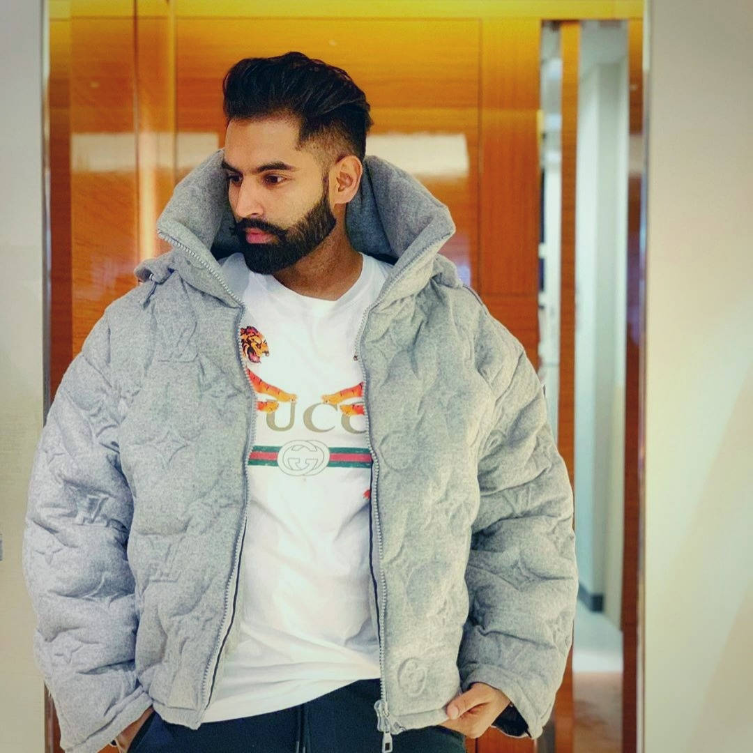 穿著灰色絎縫外套和Gucci T恤的男士站在室內木門附近。