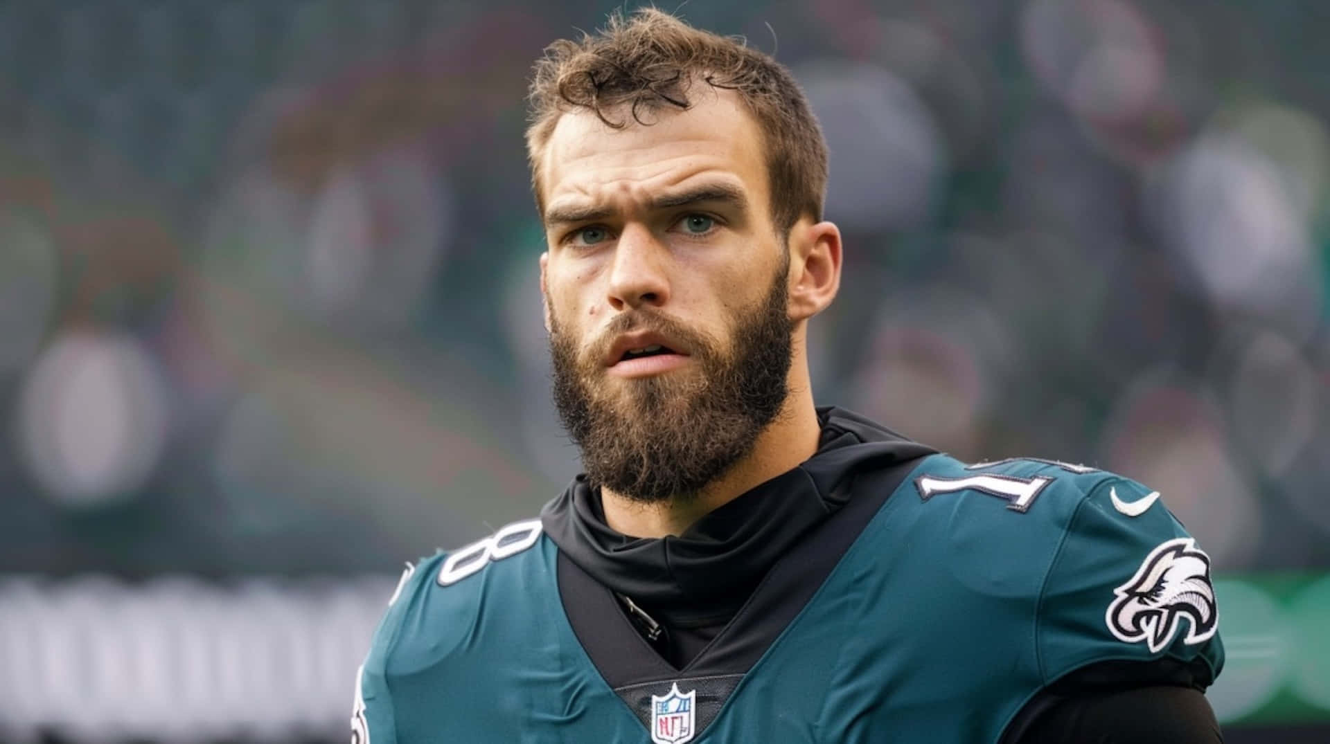  壁紙 — 一位留鬍鬚的足球員身穿綠色Eagles球衣，在模糊的球場上專注地向前看的特寫。