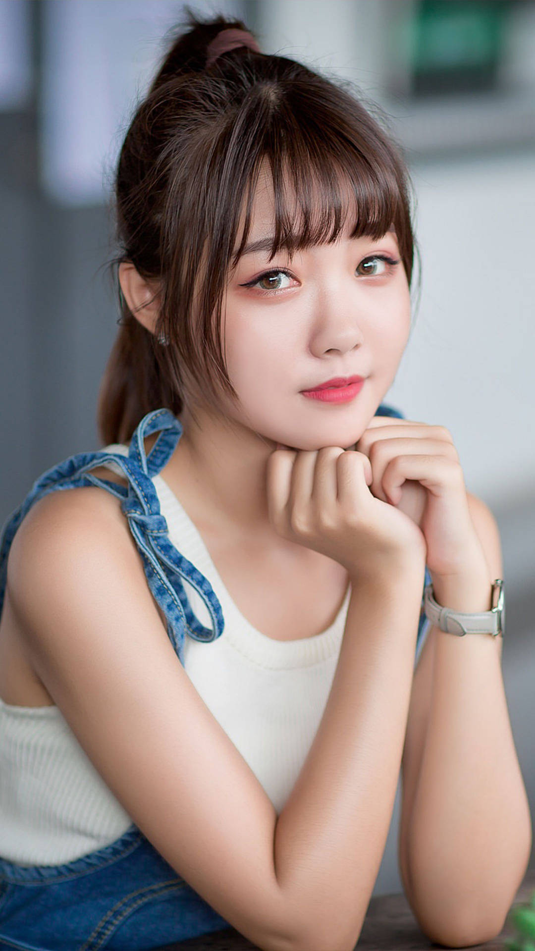 穿著牛仔吊帶褲的年輕女性在室內雙手托腮 — 女孩 壁紙