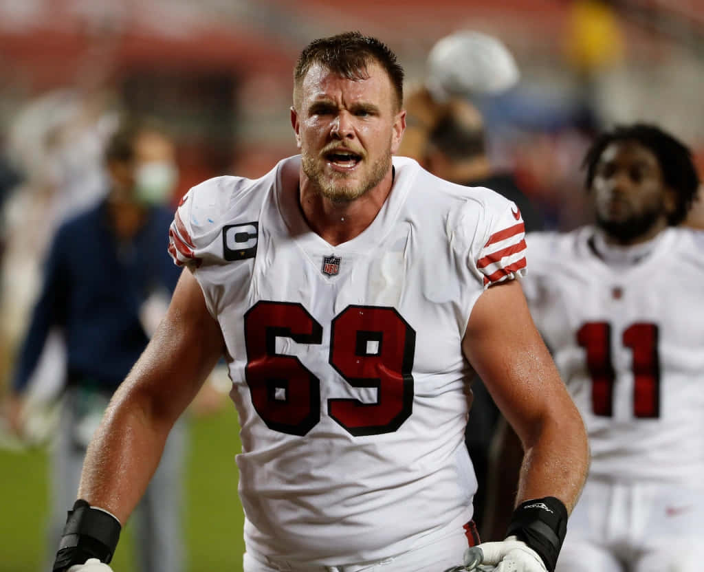 NFL美式足球員69號在夜間球場燈光下於場上咆哮。