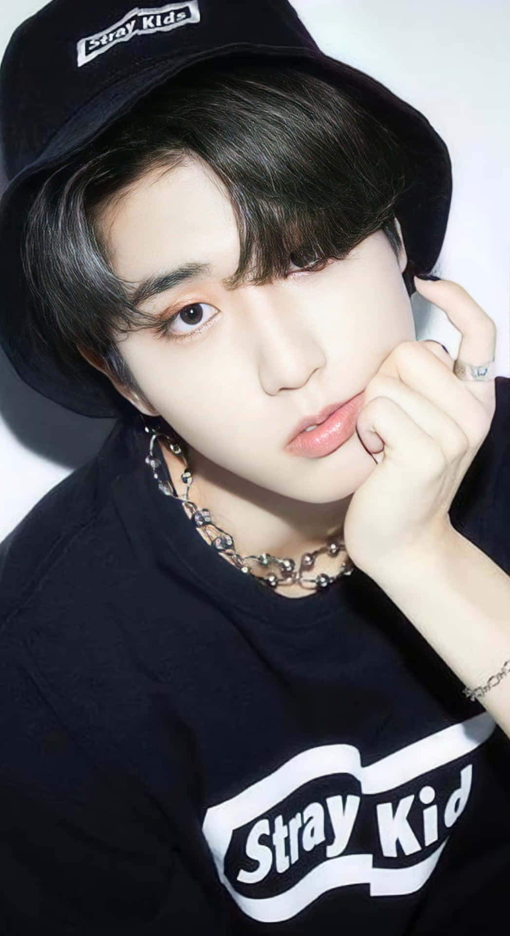  壁紙 — 一位深色頭髮的年輕男子戴著黑色漁夫帽，身穿印有「Stray Kids」標誌的T恤，托腮沉思。