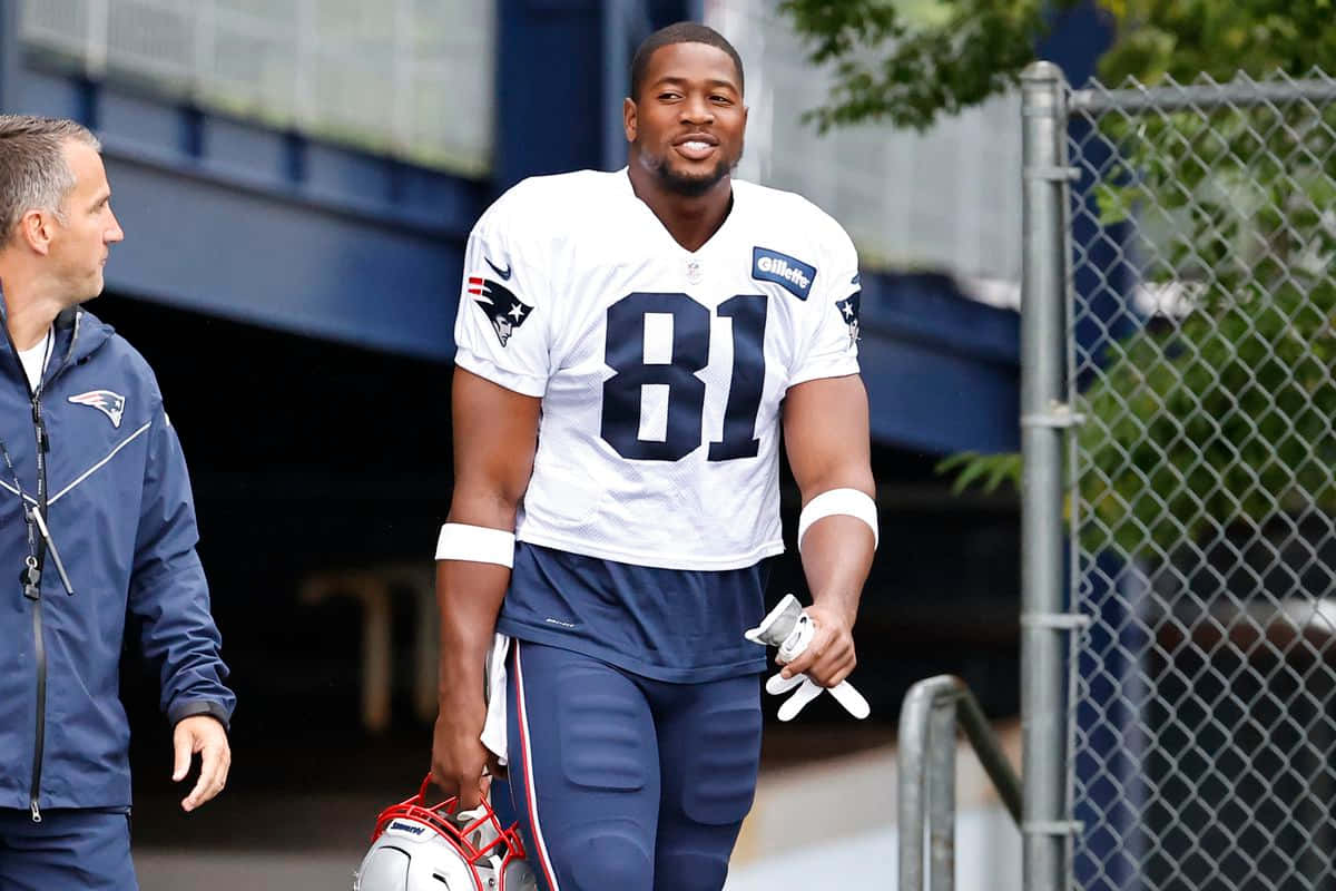 穿著白色81號球衣的NFL球員手持頭盔和手套行走