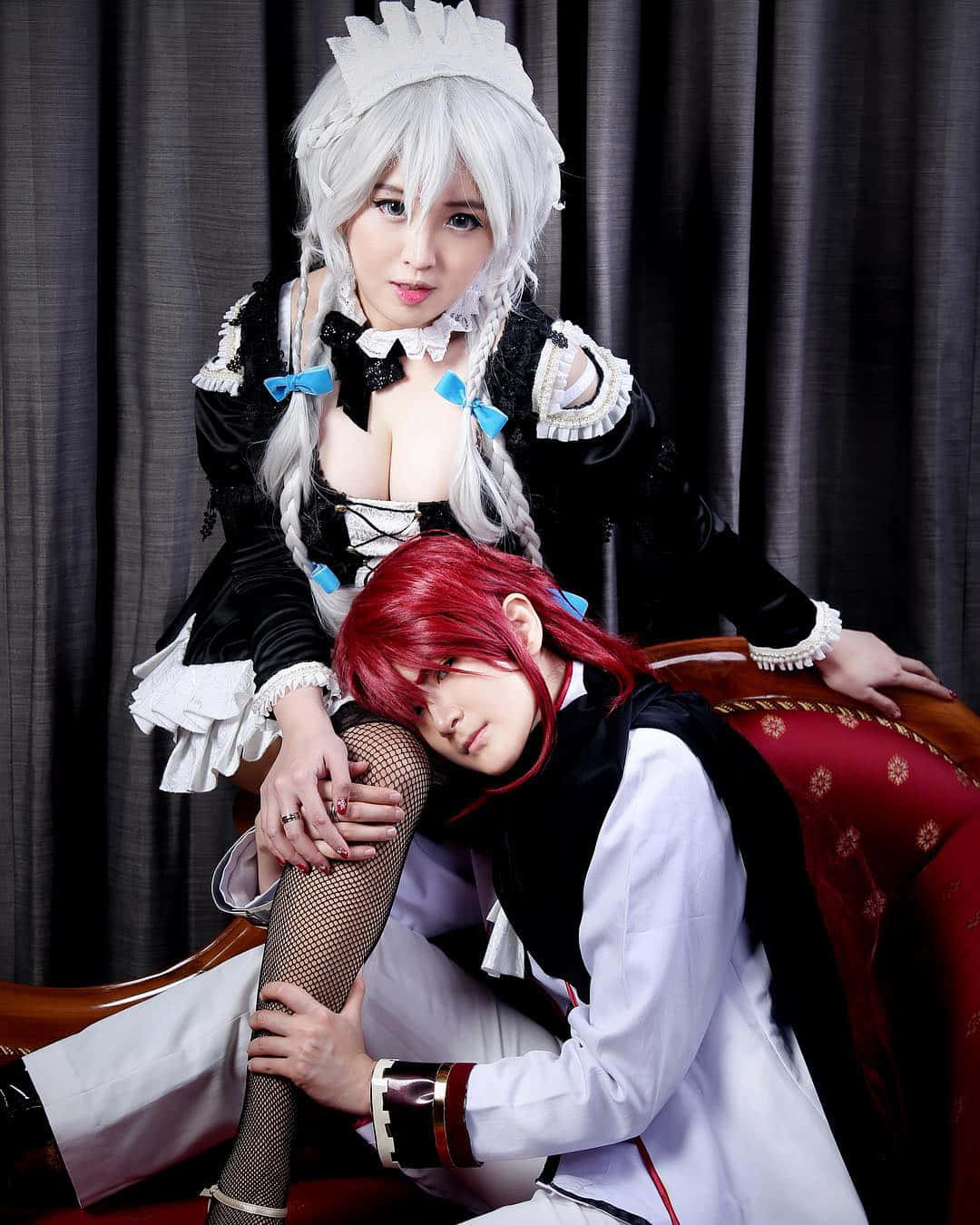  壁紙 — 一位銀髮、身穿黑白女僕裝的cosplayer坐在另一位跪在紅色椅子上、身穿白色制服、紅髮的cosplayer身上。