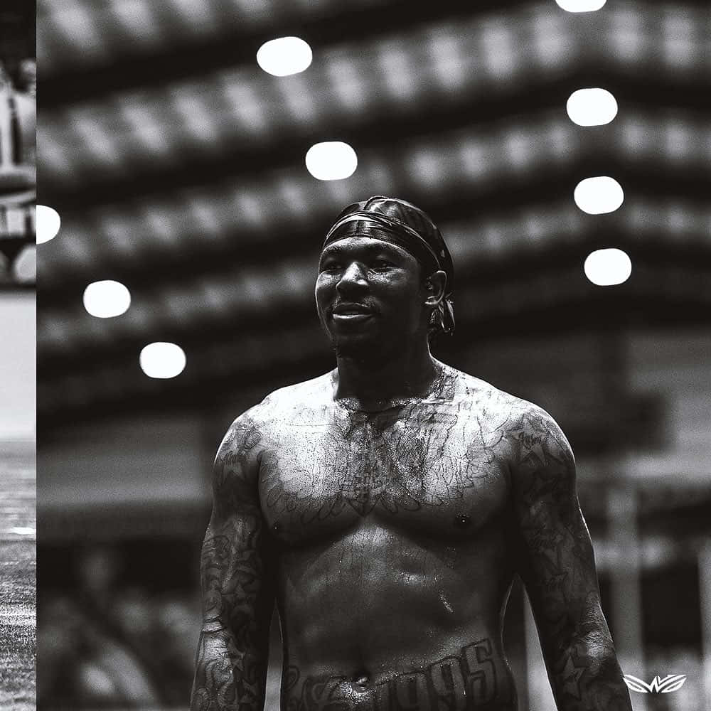 Jamaal Williams 桌布 壁紙 — 一位有紋身的運動員在明亮的場館燈光下赤裸上身，神情專注。