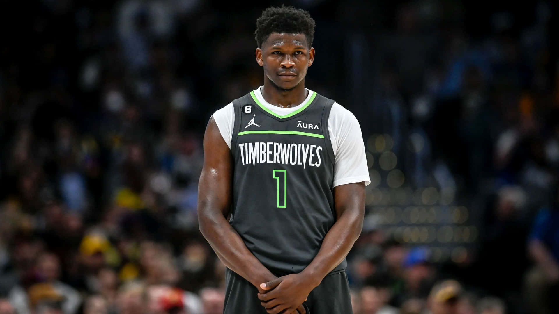  壁紙 — 一位專注的籃球運動員身穿Timberwolves球衣，在明亮的場館燈光下雙手合十站立比賽中。