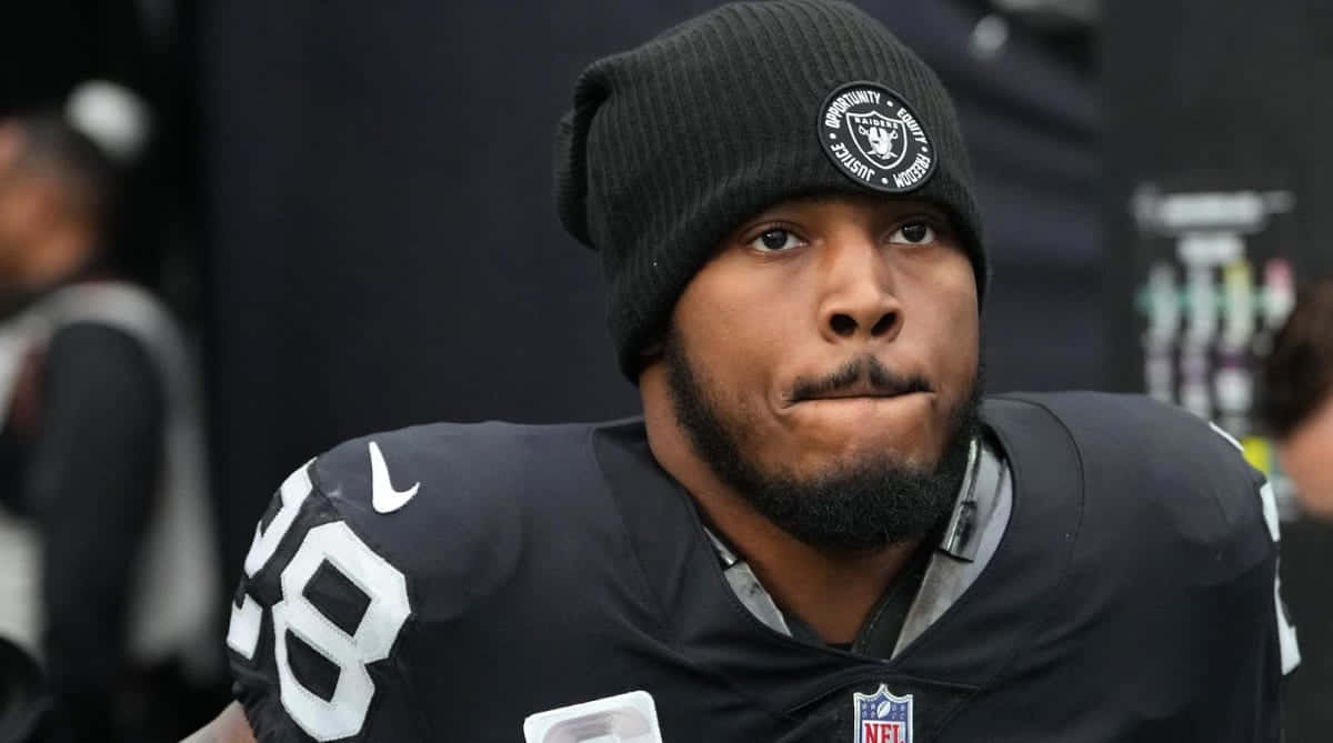  壁紙 — 一位專注的NFL美式足球員，身穿黑色Raiders球衣和冷帽，神情嚴肅地凝視前方。