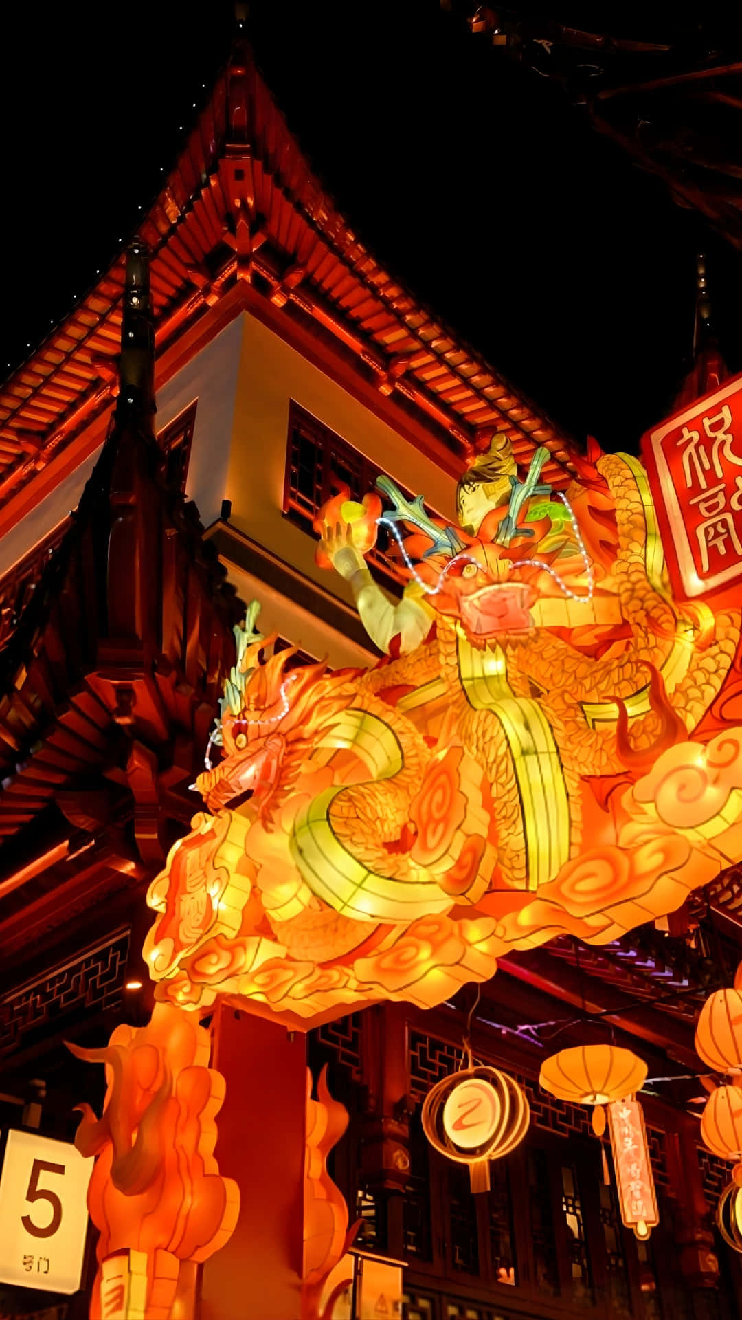  壁紙 — 一盞發光的橙色龍燈籠照亮了夜晚的傳統中式建築，下方掛著節日紙燈籠。