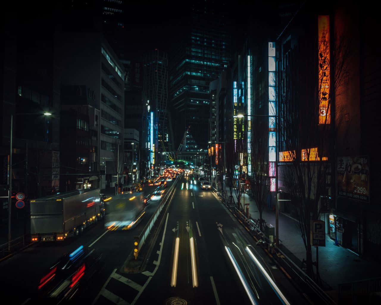 霓虹燈城市街道夜景，帶有流動的車燈軌跡和高聳的建築物。