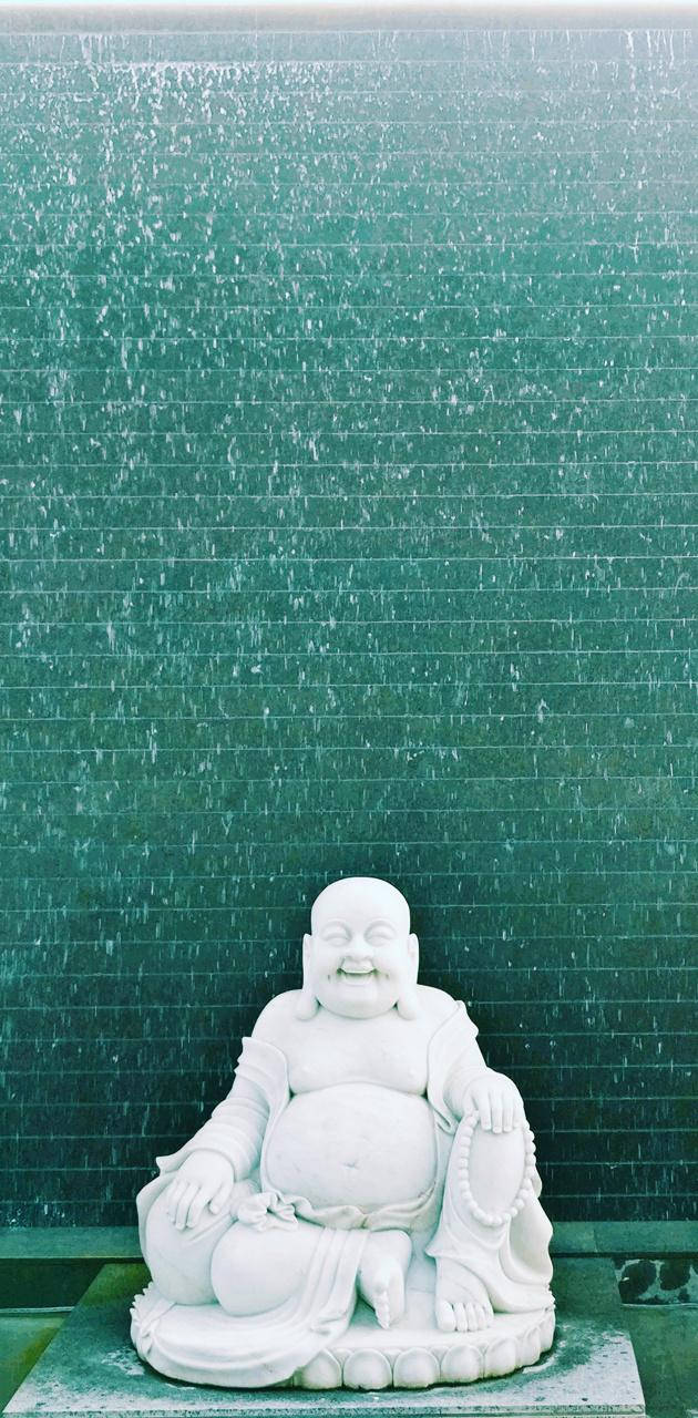 白色笑佛雕像在綠色水牆前