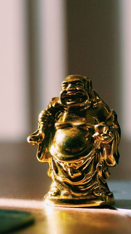 金色笑佛雕像，木質表面，柔和陽光。