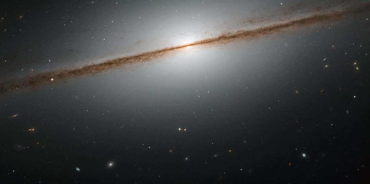  壁紙 — 一個宏偉的螺旋星系，核心明亮，塵埃臂在佈滿恆星的宇宙虛空中伸展。