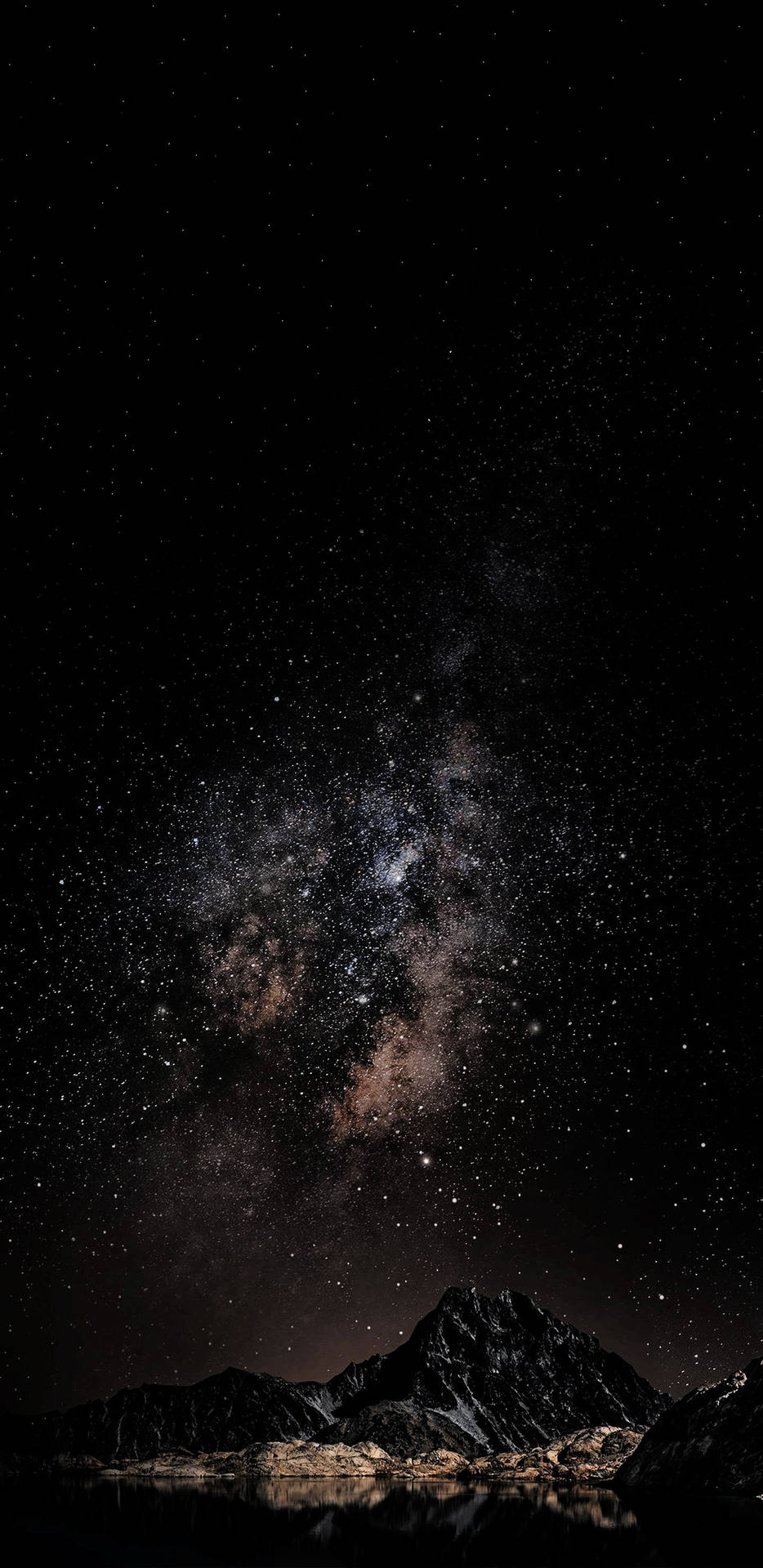 銀河星系在黑暗山脈之上，倒映在夜晚的平靜水面上。