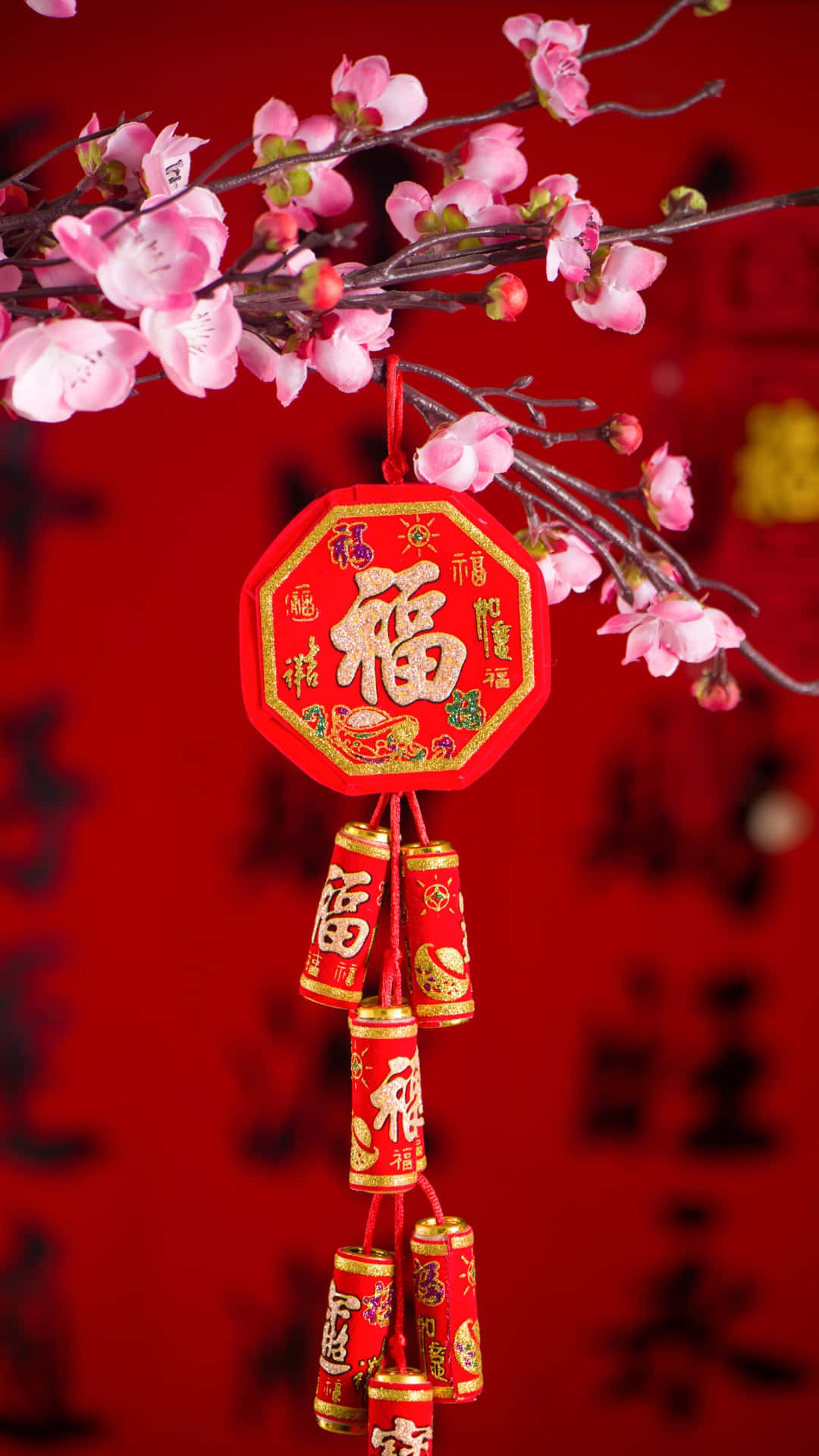  壁紙 — 一個鮮豔的紅色中國新年裝飾，帶有粉紅色的櫻花和金色書法，掛在喜慶的紅色背景上。