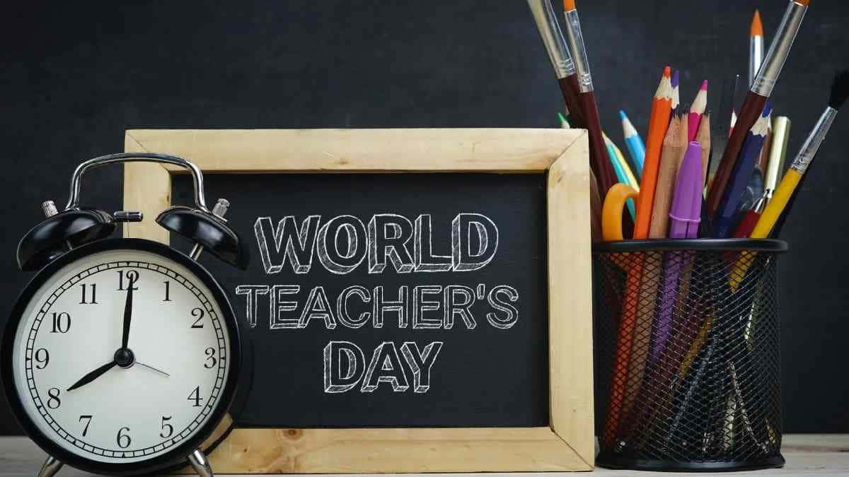  壁紙 — 一個復古鬧鐘放在一塊寫有World Teacher's Day的黑板旁邊，還有一杯色彩繽紛的鉛筆和畫筆。