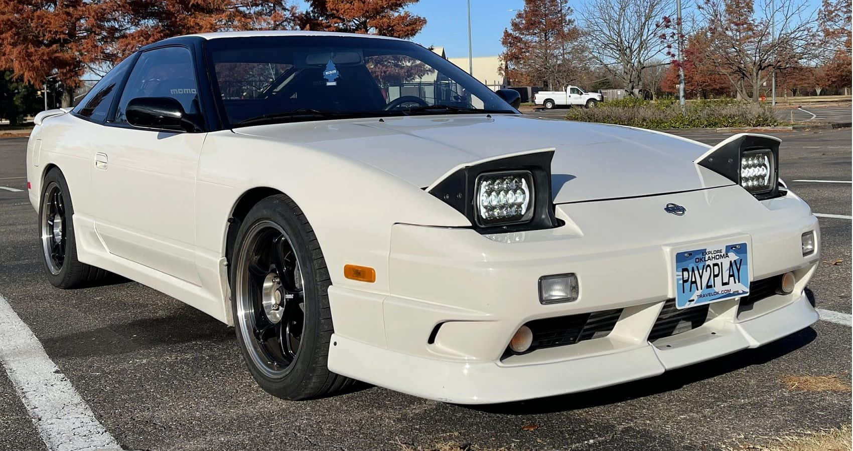  壁紙 — 一架純白色的日產300ZX跑車停泊在停車場，周圍有秋天的樹木和晴朗的藍天。