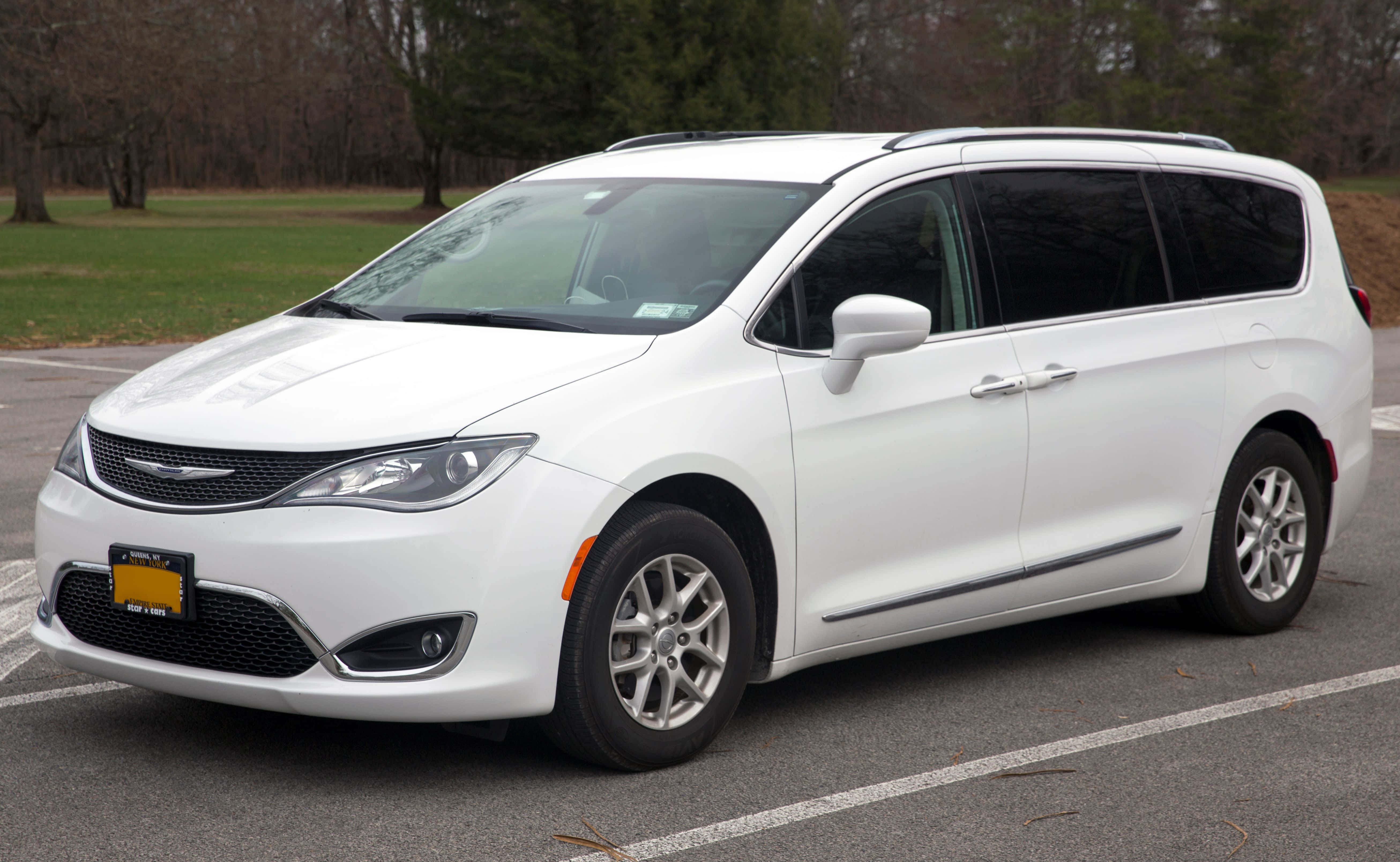 Chrysler Pacifica 桌布 壁紙 — 一架純白色的 Chrysler Pacifica 小型貨車停泊在瀝青停車場，背景有光禿的樹木和草地。