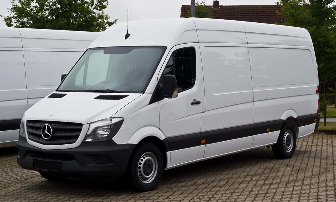 Mercedes Benz Sprinter 桌布 壁紙 — 一架純白色的Mercedes-Benz Sprinter客貨車停泊在鋪砌的停車場，背景有樹木和另一輛客貨車。