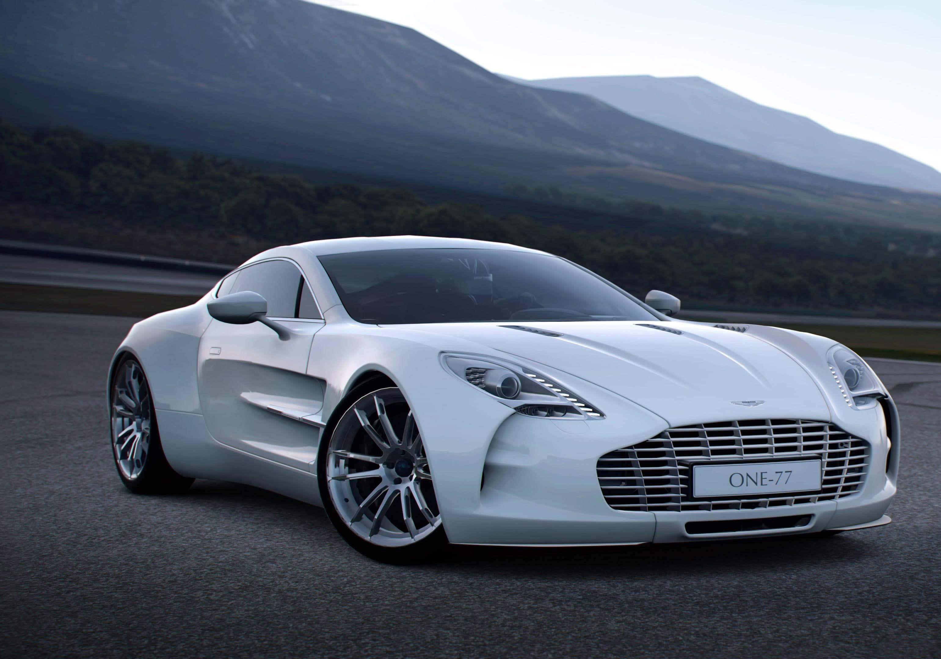Aston Martin One-77 桌布 壁紙 — 一架流線型的白色Aston Martin One-77跑車在賽道上奔馳，背景是霧氣繚繞的山巒。