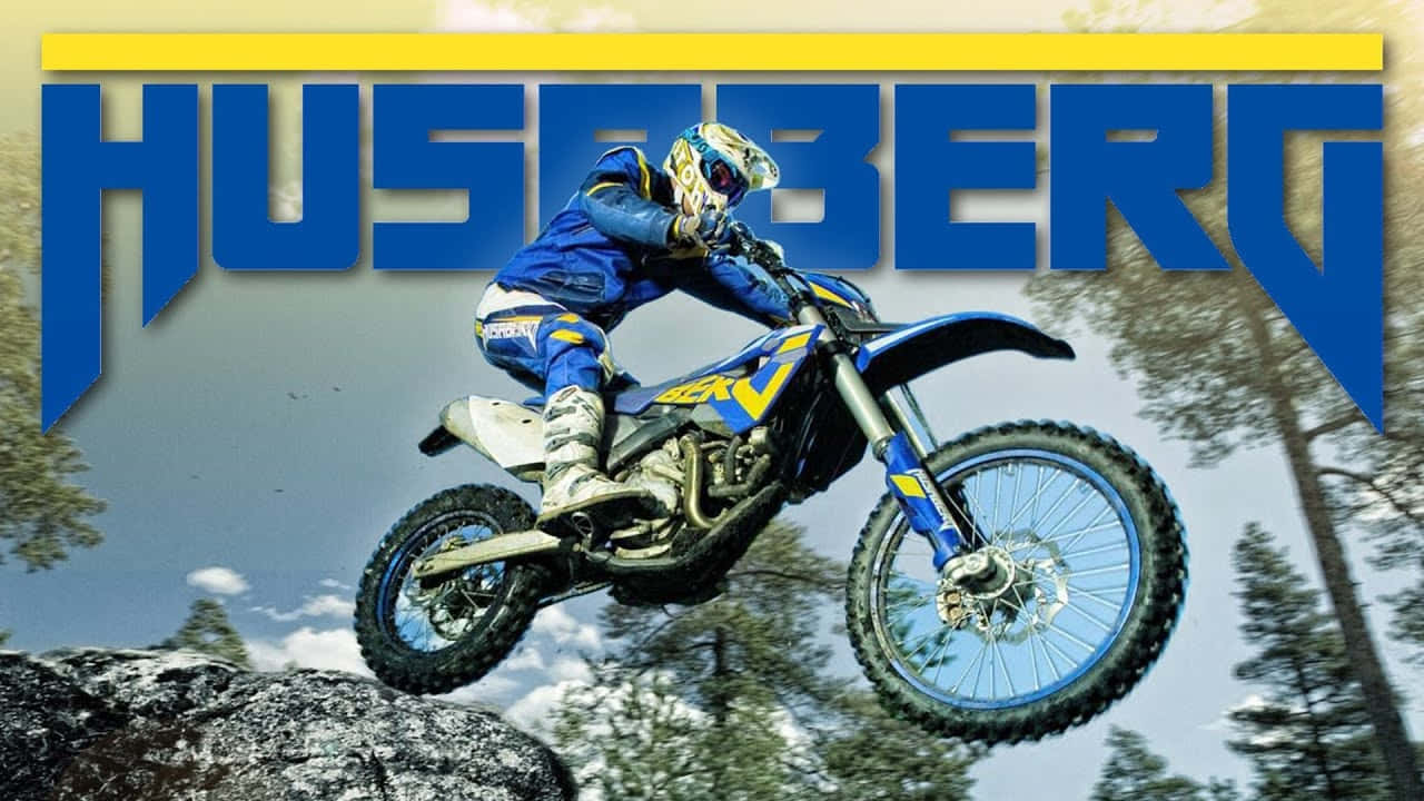  壁紙 — 一名身穿藍色裝備的越野電單車手，駕駛藍黃色的 Husqvarna 電單車，在松樹林立的岩石地形上空飛翔。