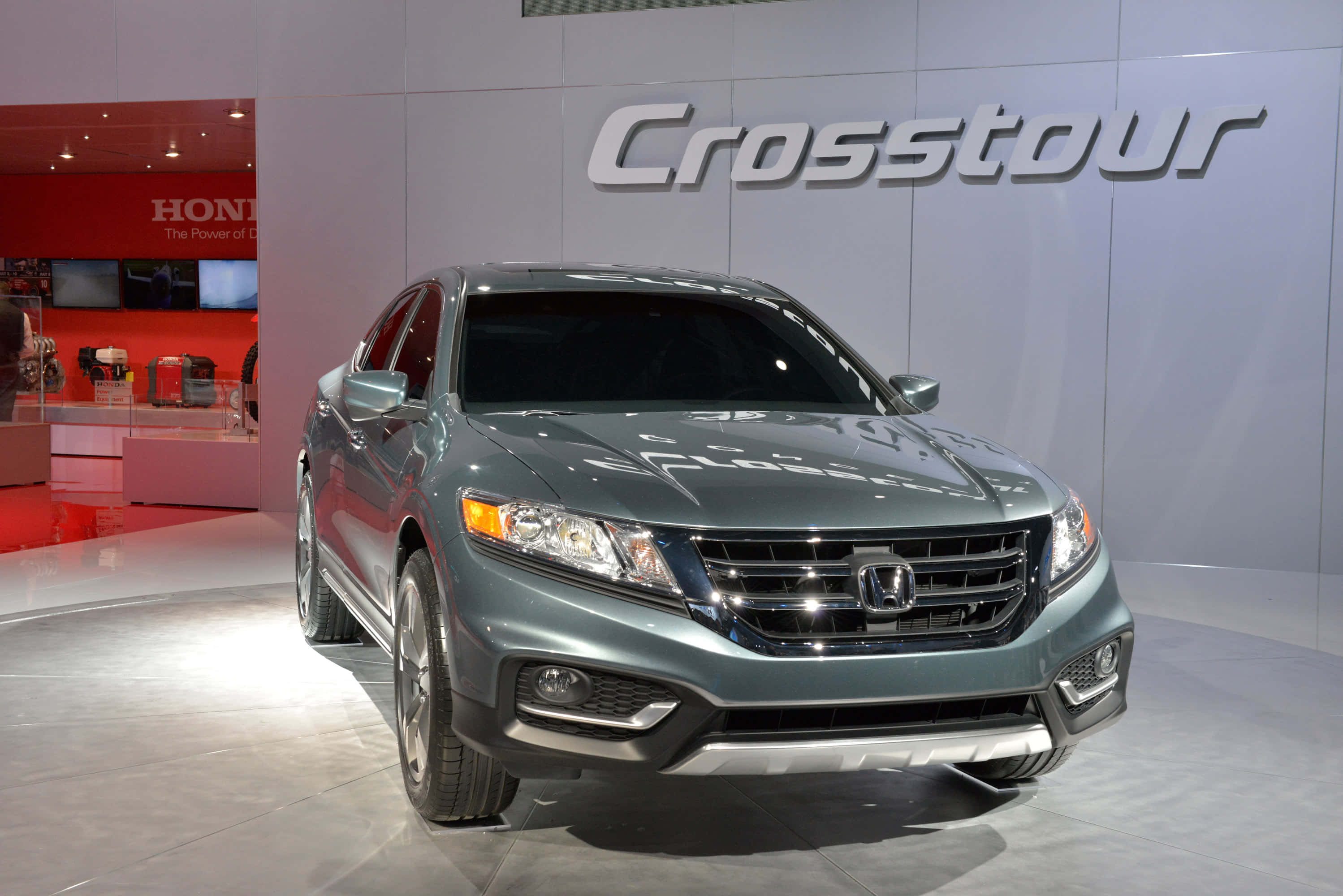 Honda Crosstour 桌布 壁紙 — 一輛時尚的金屬綠色本田Crosstour轎車在明亮的展廳燈光下，在拋光地板上閃閃發光，背後有品牌標誌。