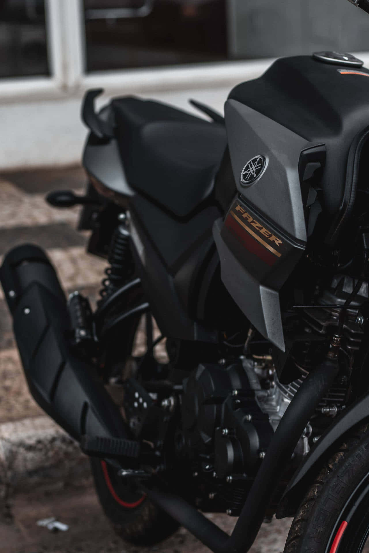  壁紙 — 一輛時尚黑色Yamaha Fazer電單車停泊在石頭表面上，背景為模糊建築物的特寫。