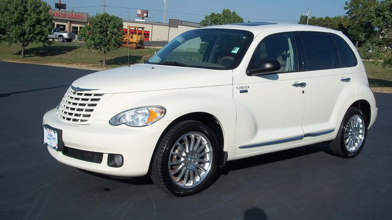 Chrysler Pt Cruiser 桌布 壁紙 — 一輛純白色的克萊斯勒 PT Cruiser 停在瀝青路上，背景有樹木和一間車庫門公司。