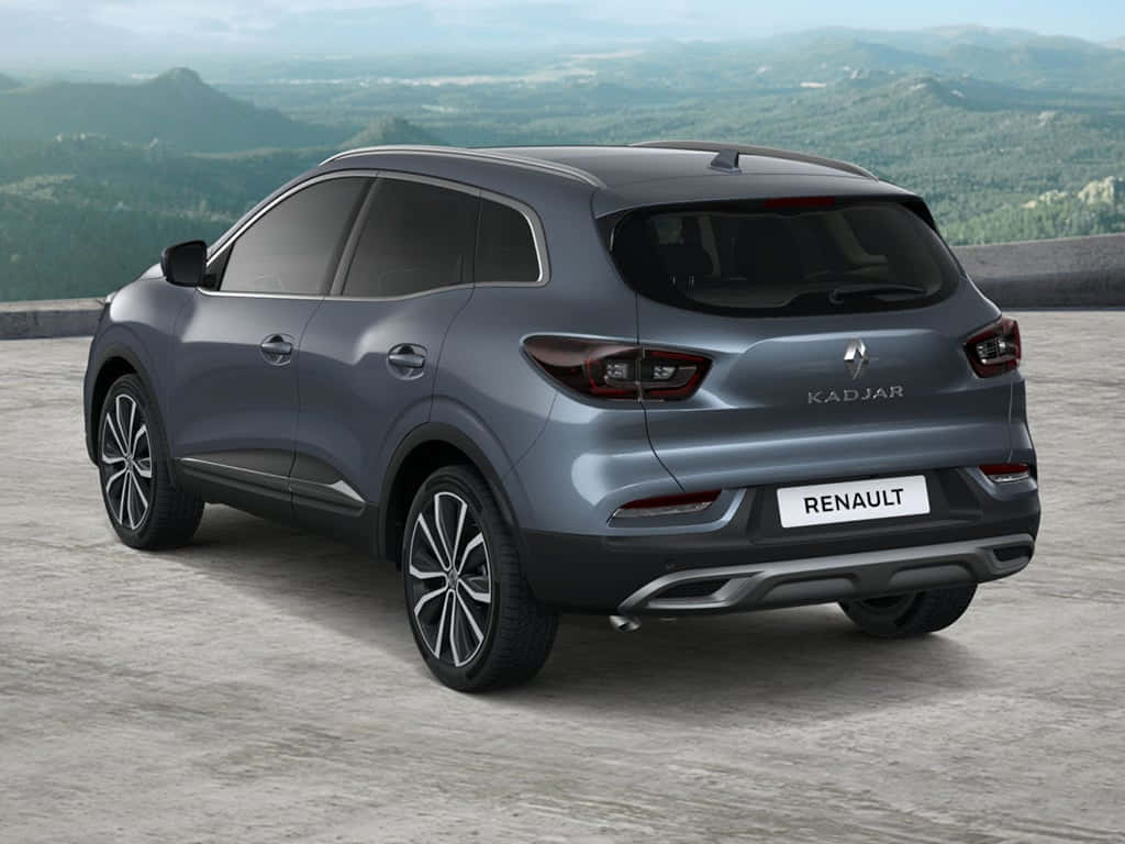  壁紙 — 一輛流線型灰色雷諾 Kadjar SUV 停泊在混凝土觀景台上，背景是起伏的綠色山丘和遠處的山脈。