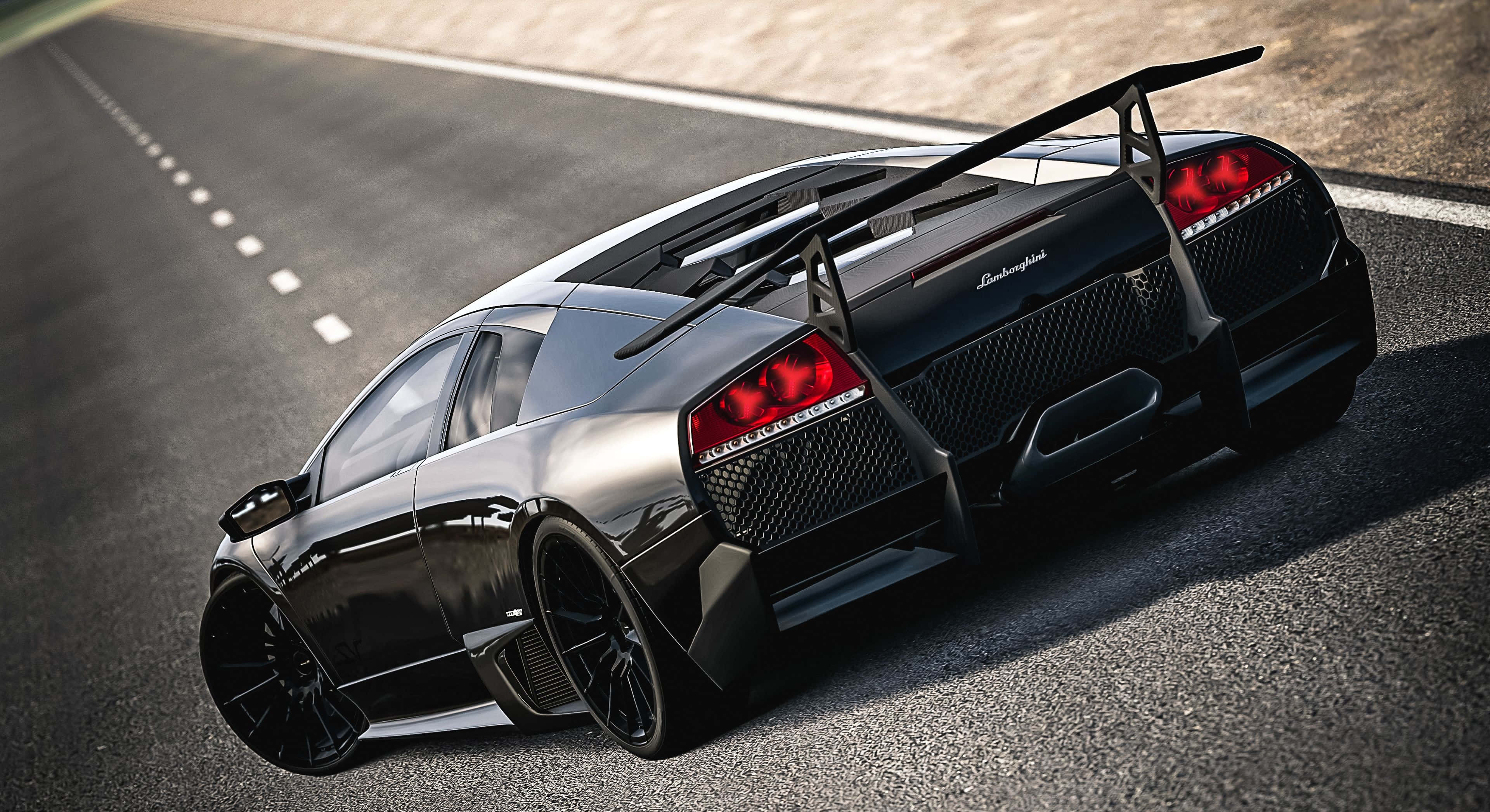 Lamborghini Murciélago 桌布 壁紙 — 一輛時尚的黑色林寶堅尼跑車，帶有發光的紅色尾燈，在陽光明媚的瀝青路上飛馳。