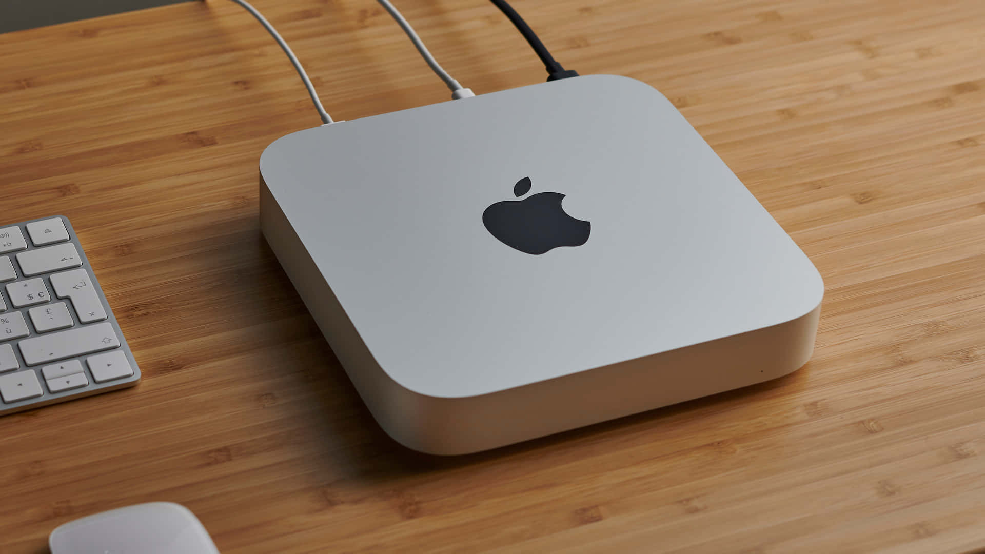 色彩繽紛的 Mac 蝴蝶特寫 壁紙 — 一部時尚的銀色 Apple Mac mini 放置在溫暖的竹桌上，旁邊有相配的鍵盤和滑鼠。