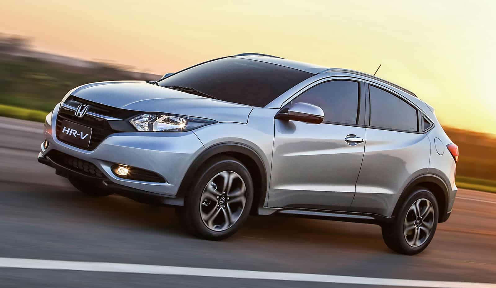 Honda Hr-v 桌布 壁紙 — 一輛銀色本田HR-V SUV在日落時分沿著道路飛馳，帶有模糊的動態和溫暖的金色光線。