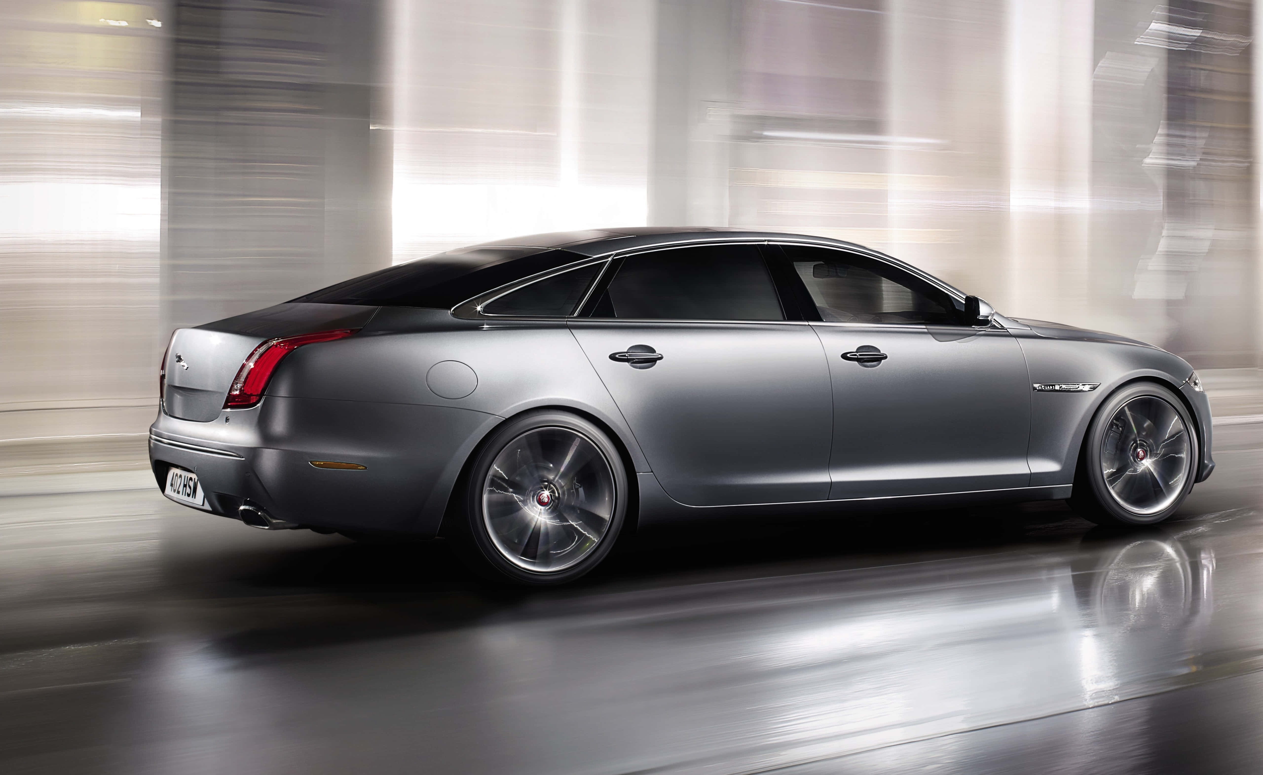 Jaguar Xjr 桌布 壁紙 — 一輛流線型的銀色積架房車穿過模糊的城市隧道，動態模糊強調了速度和奢華。
