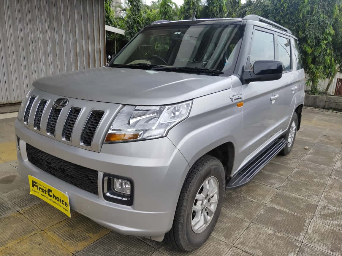  壁紙 — 一輛銀色Mahindra Bolero SUV停泊在瓷磚車道上，背景有綠色樹木。