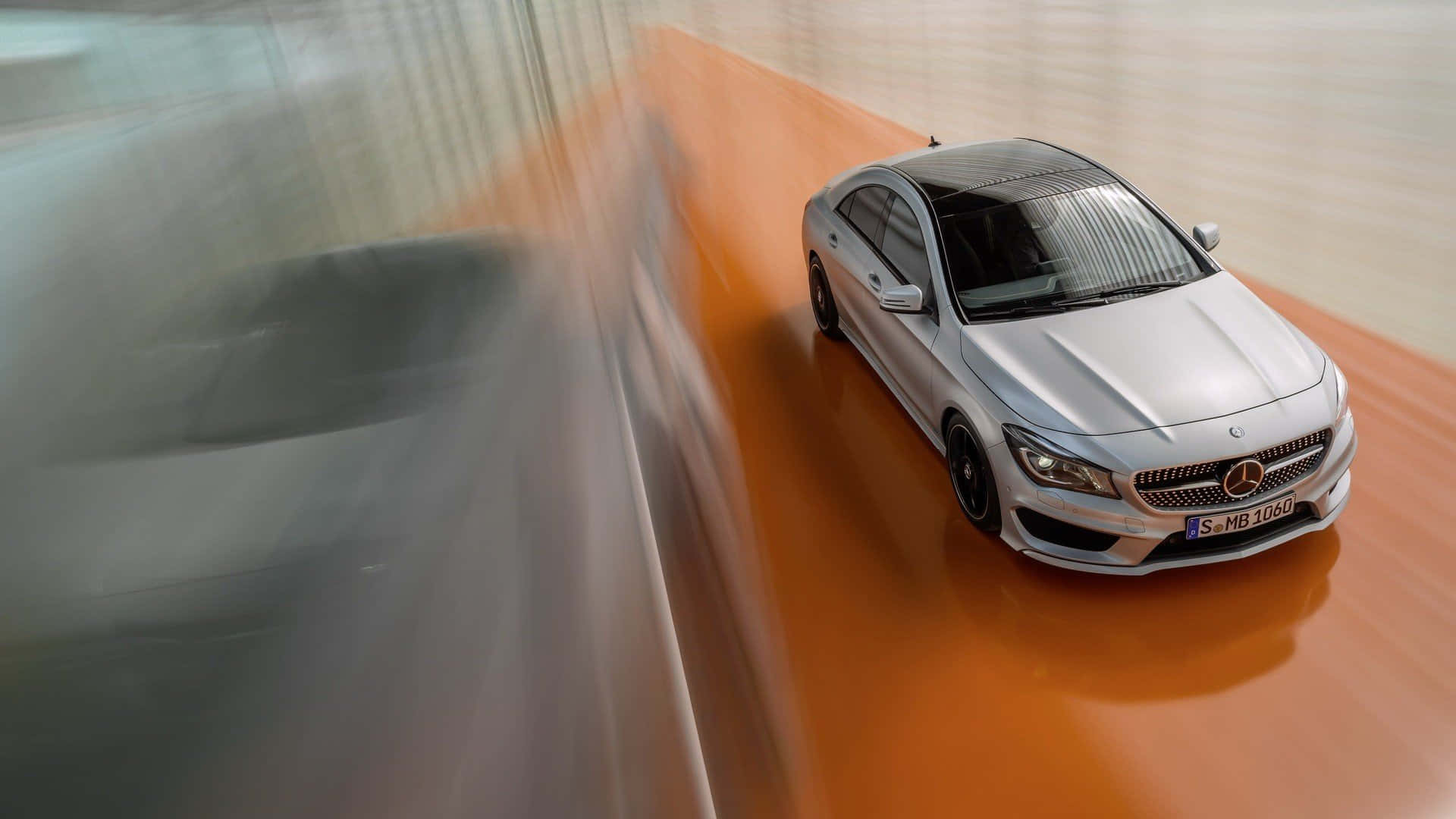 Mercedes Benz Cla-class 桌布 壁紙 — 一輛銀色平治CLA房車在橙色賽道上高速行駛，動態模糊傳達高速與時尚設計。