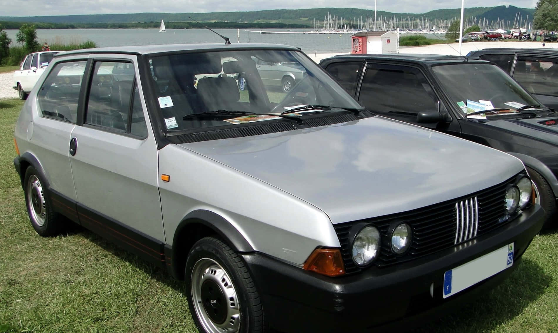Fiat Ritmo 桌布 壁紙 — 一架銀色Fiat Tipo掀背車停在湖邊草地上，背景有帆船。