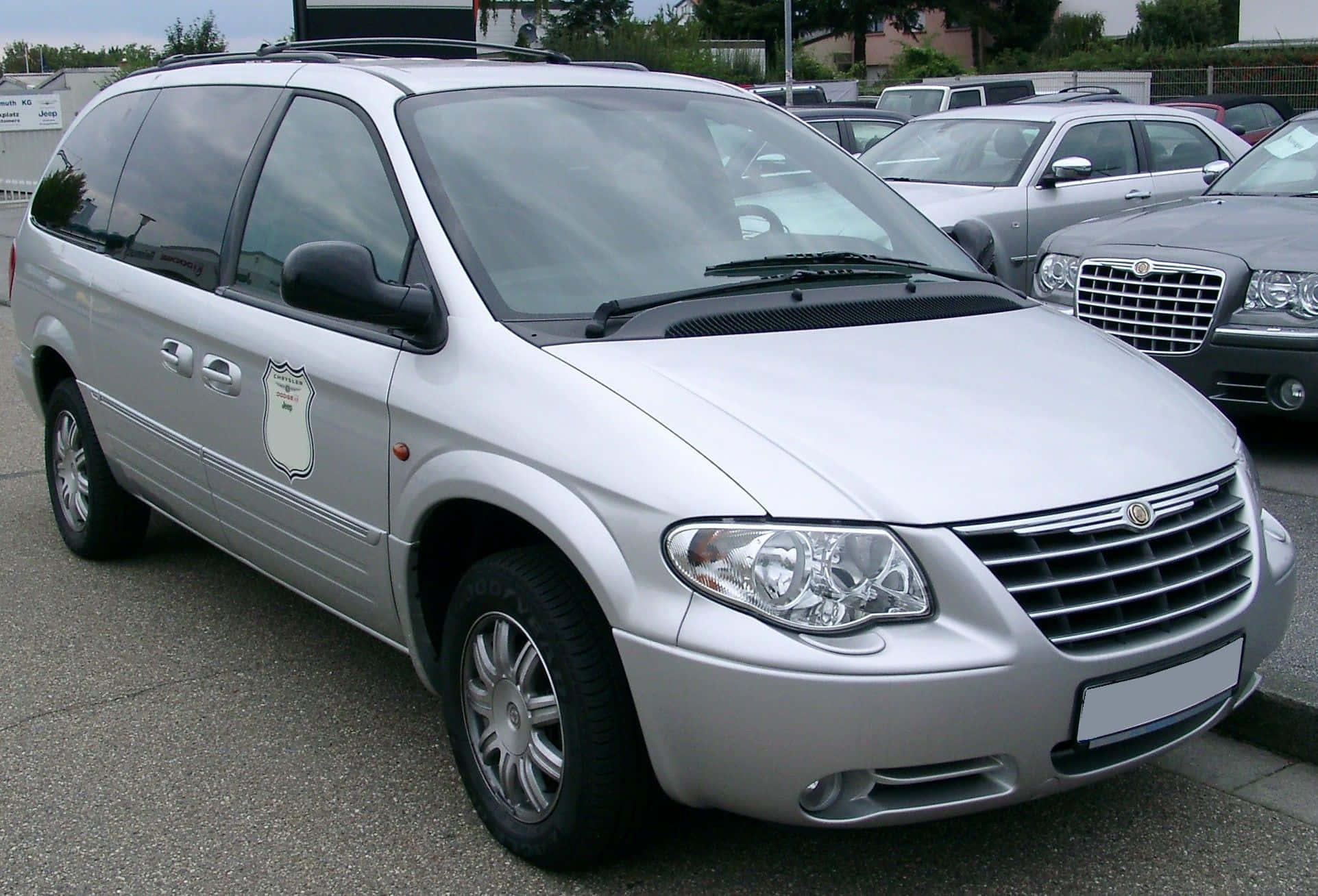 Chrysler Voyager 桌布 壁紙 — 一輛銀色警用小型貨車停泊在停車場，背景可見其他車輛。