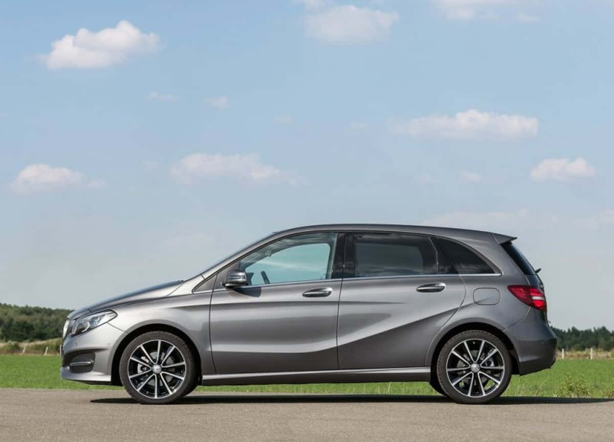 Mercedes Benz B-class 桌布 壁紙 — 一架時尚的銀色 Mercedes-Benz 旅行車停泊在鋪砌的道路上，天空湛藍，白雲點綴。