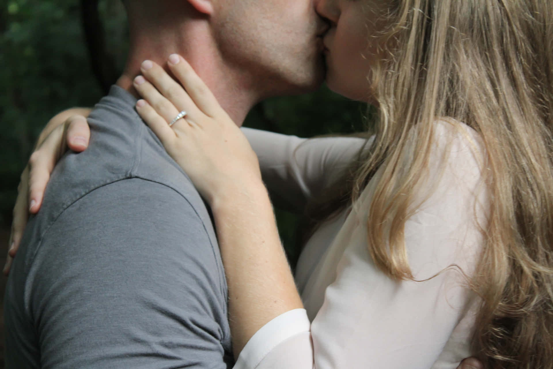 一對情侶在戶外接吻，女方手上可見結婚戒指。