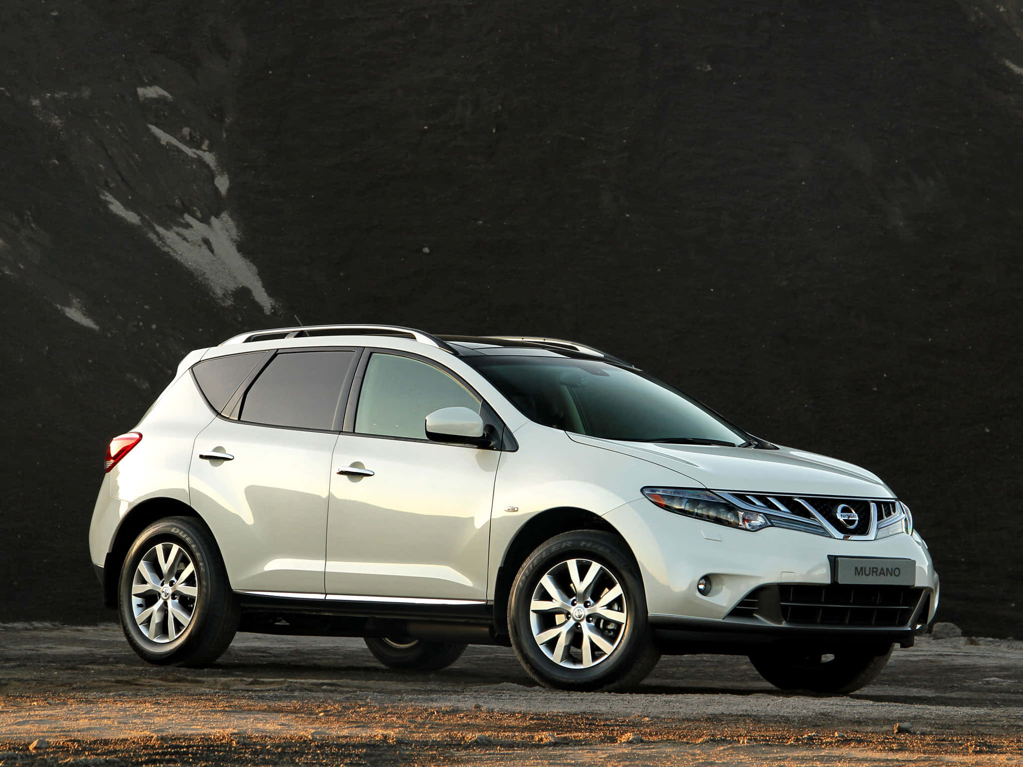 Nissan Murano 桌布 壁紙 — 一架時尚的白色日產Murano SUV停靠在帶有金色地面點綴的深色紋理牆前。