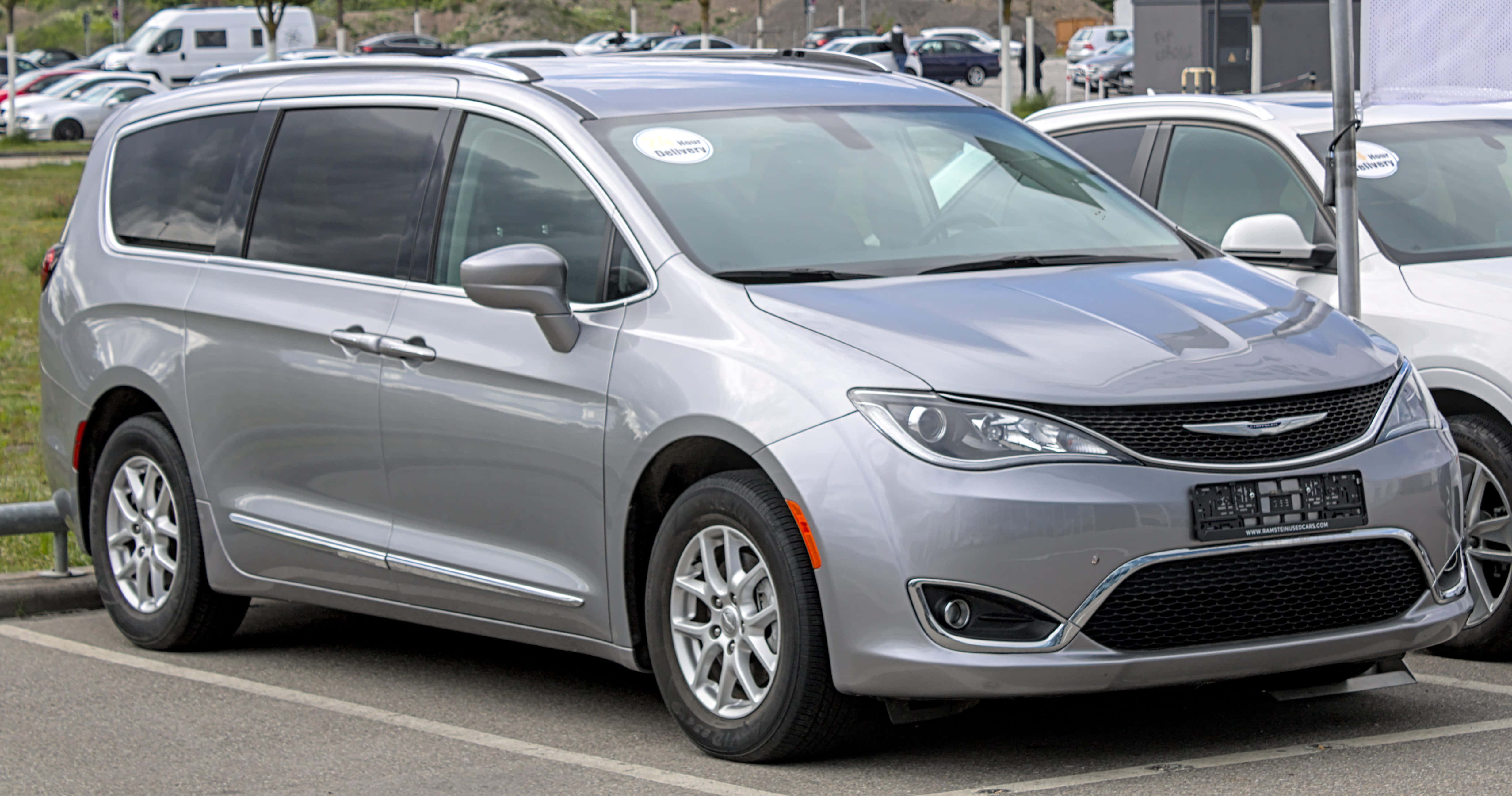 Chrysler Pacifica 桌布 壁紙 — 一架時尚的銀色 Chrysler Pacifica 小型貨車在明亮的日光下與其他汽車一起停泊在停車場。