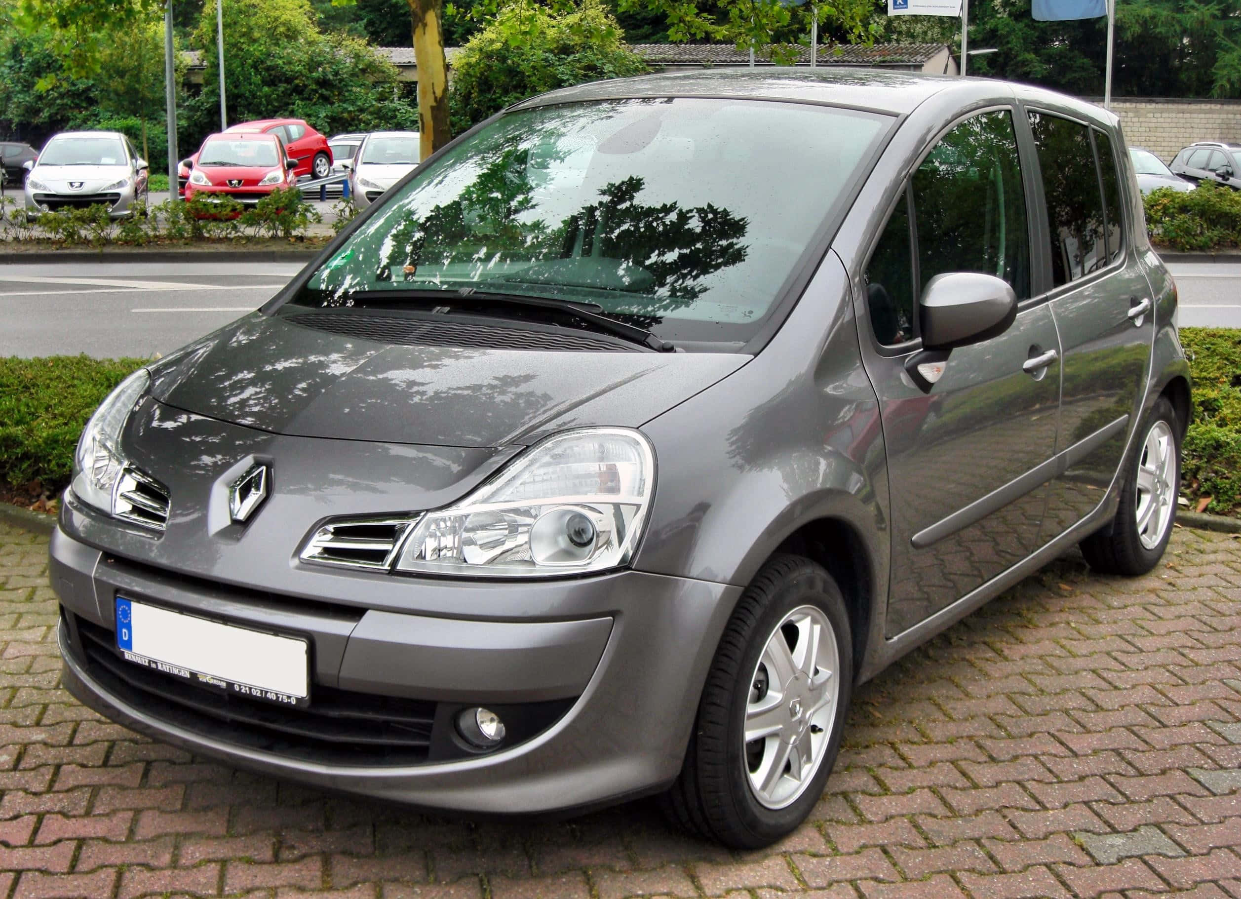 Renault Modus 桌布 壁紙 — 一架流線型灰色雷諾Scenic停泊在磚砌停車場，背景有綠化及其他車輛。