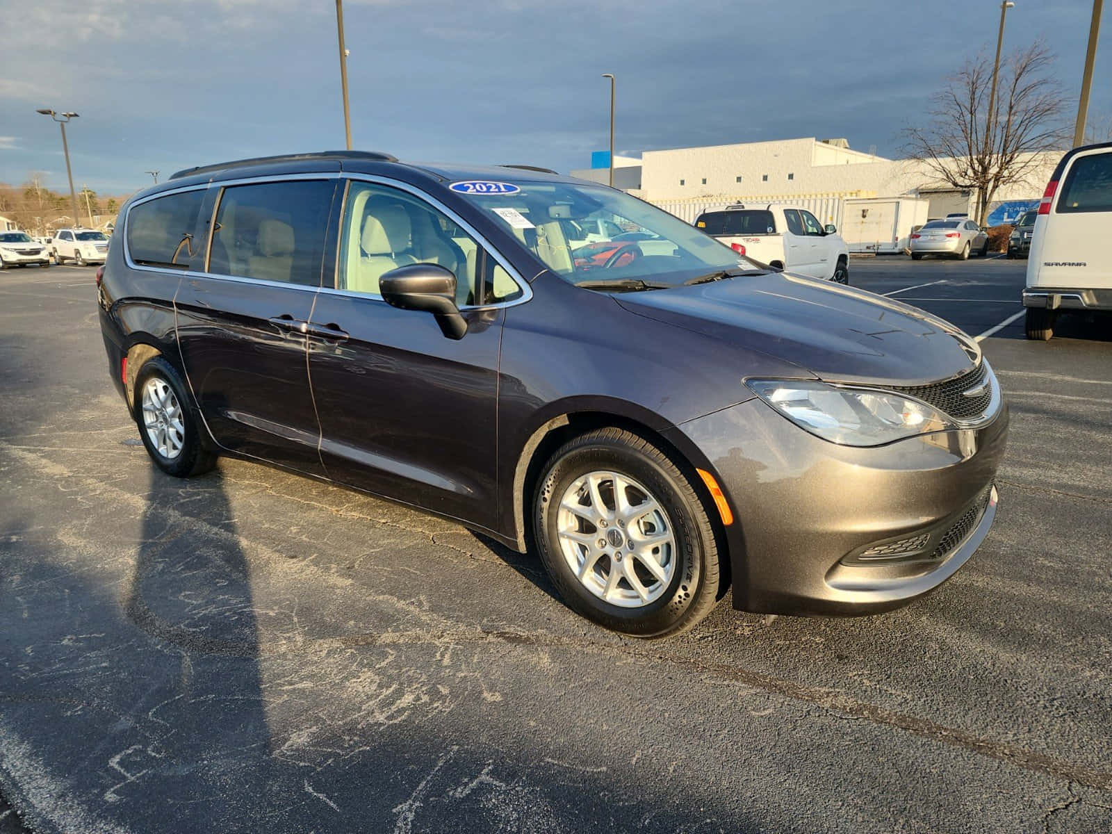 Chrysler Voyager 桌布 壁紙 — 一架時尚深灰色2021年克萊斯勒Pacifica小型貨車停泊在停車場，天空多雲，附近有其他車輛。