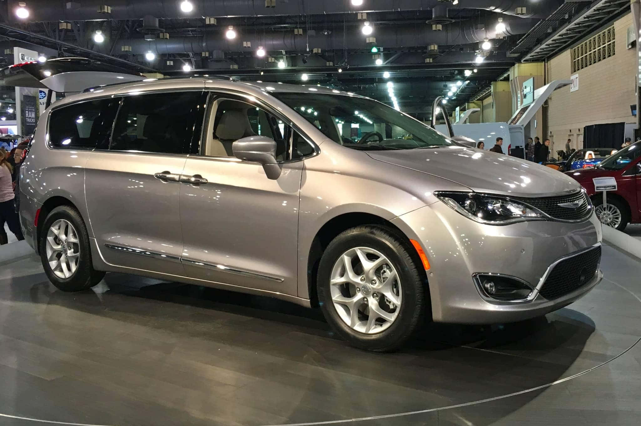 Chrysler Pacifica 桌布 壁紙 — 一輛時尚的銀色小型貨車在車展上展出，地板拋光，天花燈光亮。
