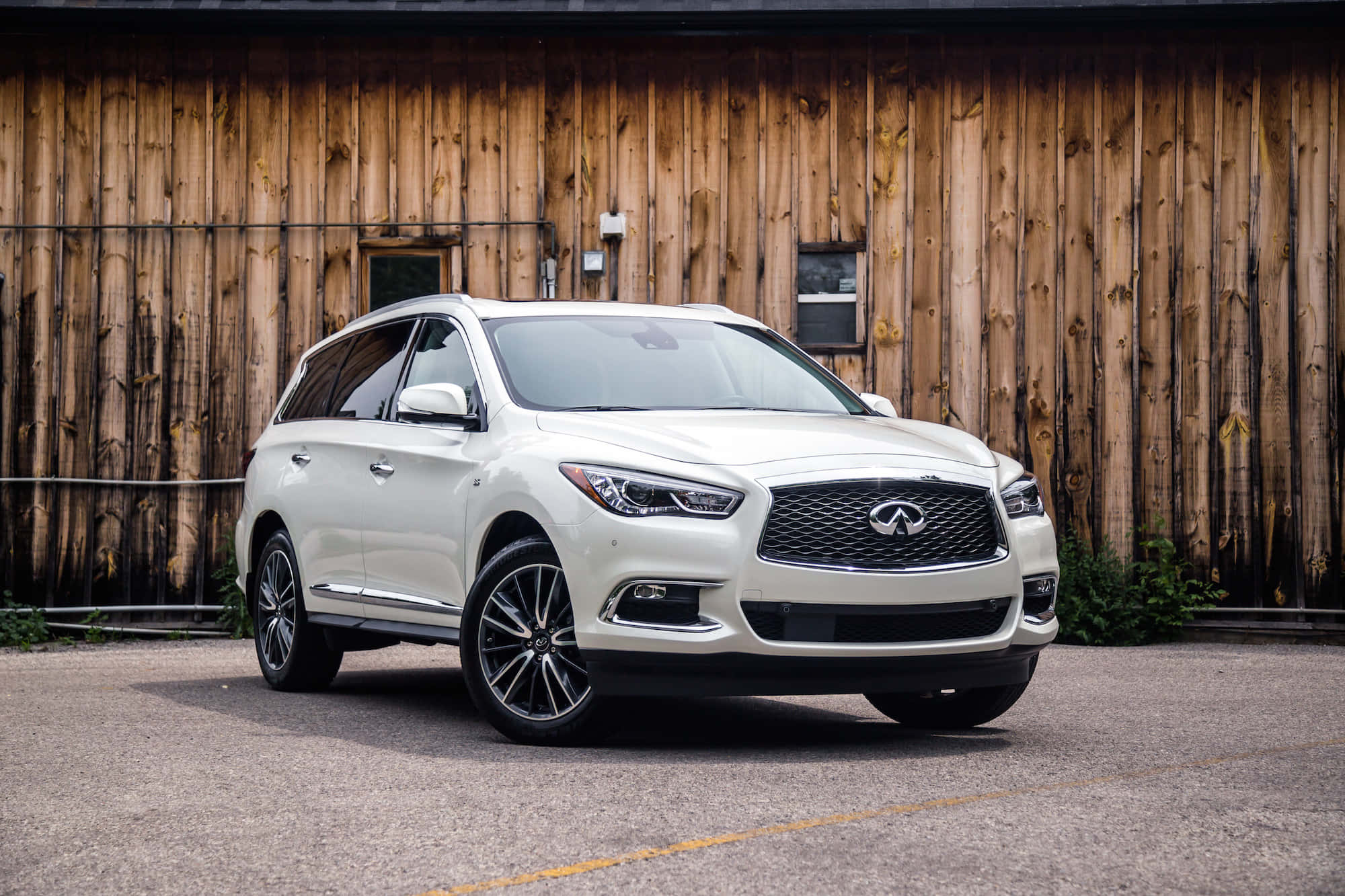Infiniti Qx60 桌布 壁紙 — 一輛純白色的 Infiniti QX60 SUV 停放在一座質樸的木製穀倉前，穀倉有風化的木板和小窗戶。