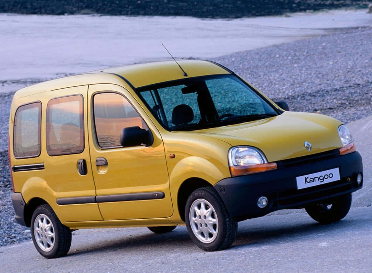 Renault Kangoo 桌布 壁紙 — 一輛亮黃色的雷諾Kangoo客貨車停在碎石路邊，背景有雪。