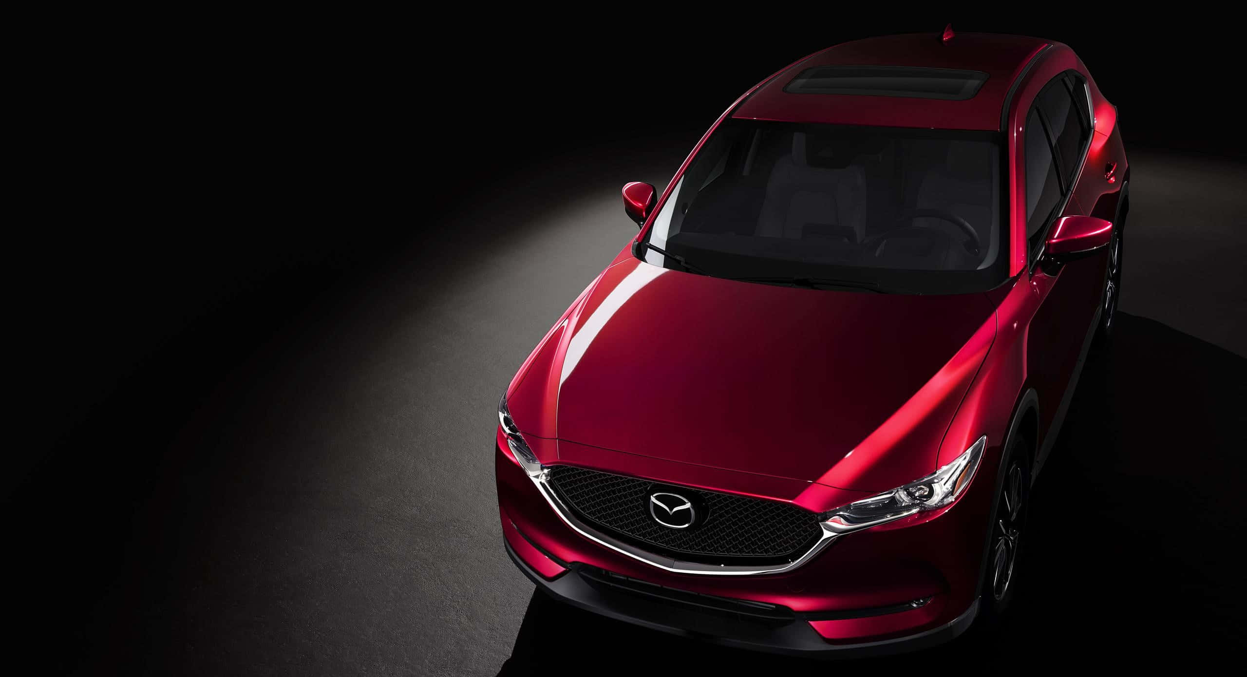 Mazda Cx-30 桌布 壁紙 — 一輛亮紅色Mazda SUV在黑色工作室背景上被戲劇性聚光燈照亮。