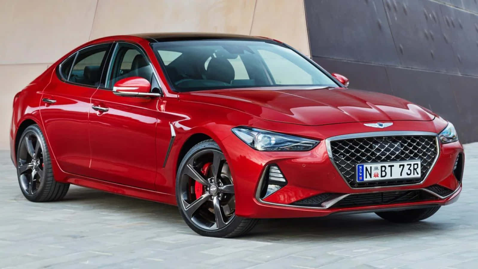 Genesis G70 桌布 壁紙 — 一輛亮紅色的Genesis G70運動轎車停泊在現代混凝土牆旁，配備黑色合金輪圈。